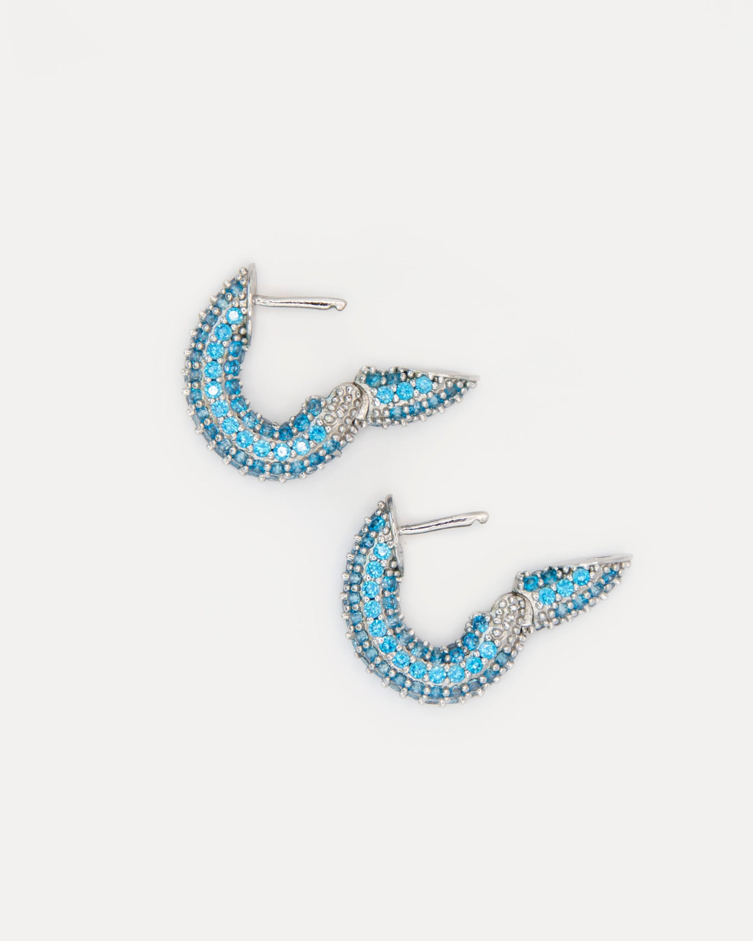 Close-up of Sparkles Earrings Blue — silver-tone mini hoops with bright blue cubic zirconia, reflecting ocean hues and adding a modern, elegant sparkle.