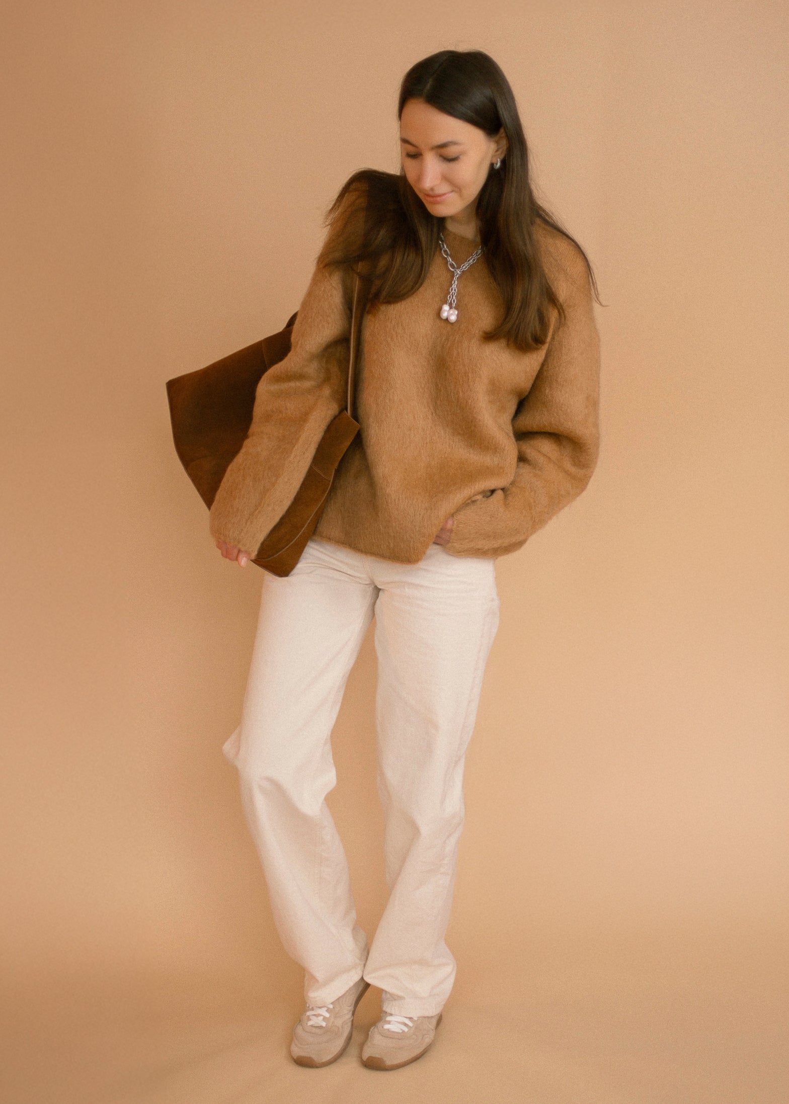 Full outfit shot featuring the Silver Rain necklace from Jewell Reef, paired with a caramel sweater, white jeans, and a suede bag.