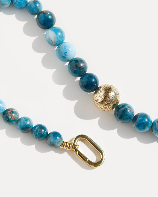 Ocean View Necklace 
Detailed close-up view showcasing the striking blue apatite beads and the textured 18K gold-plated brass bead, alongside the sophisticated golden clasp. This image highlights the natural quality and rich color variations within the apatite stones, emphasizing the modern craftsmanship and secure closure. Ideal for those who appreciate unique, high-quality jewelry with an artistic touch, ensuring both style and durability for a distinctive choker.