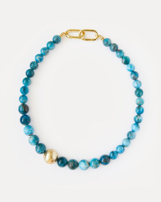 Ocean View Necklace 
Bold apatite beaded choker featuring large, vibrant blue apatite stones. It incorporates a unique, asymmetrically placed textured 18K gold-plated brass bead, adding a distinct contemporary accent. This statement jewelry piece elegantly combines natural beauty with modern design, perfect for special occasions, elevating everyday style, or as a thoughtful gift for discerning jewelry enthusiasts seeking timeless elegance.