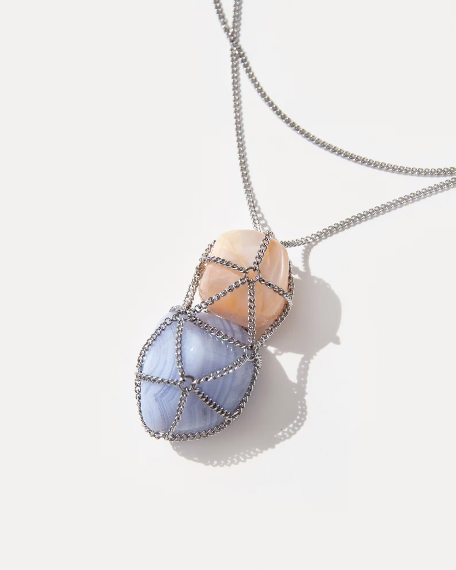 Close-up of Angel Skin Necklace pendant - blue lace agate and sunstone wrapped in a silver net. Unique pastel gemstone necklace by Jewell Reef.