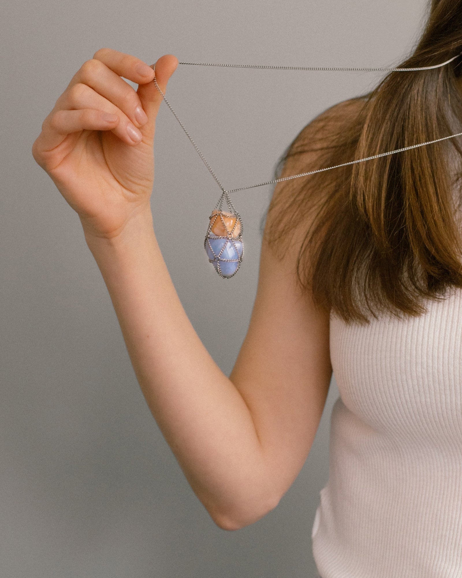 Close-up of Angel Skin Necklace pendant with sunstone and blue lace agate in steel netting