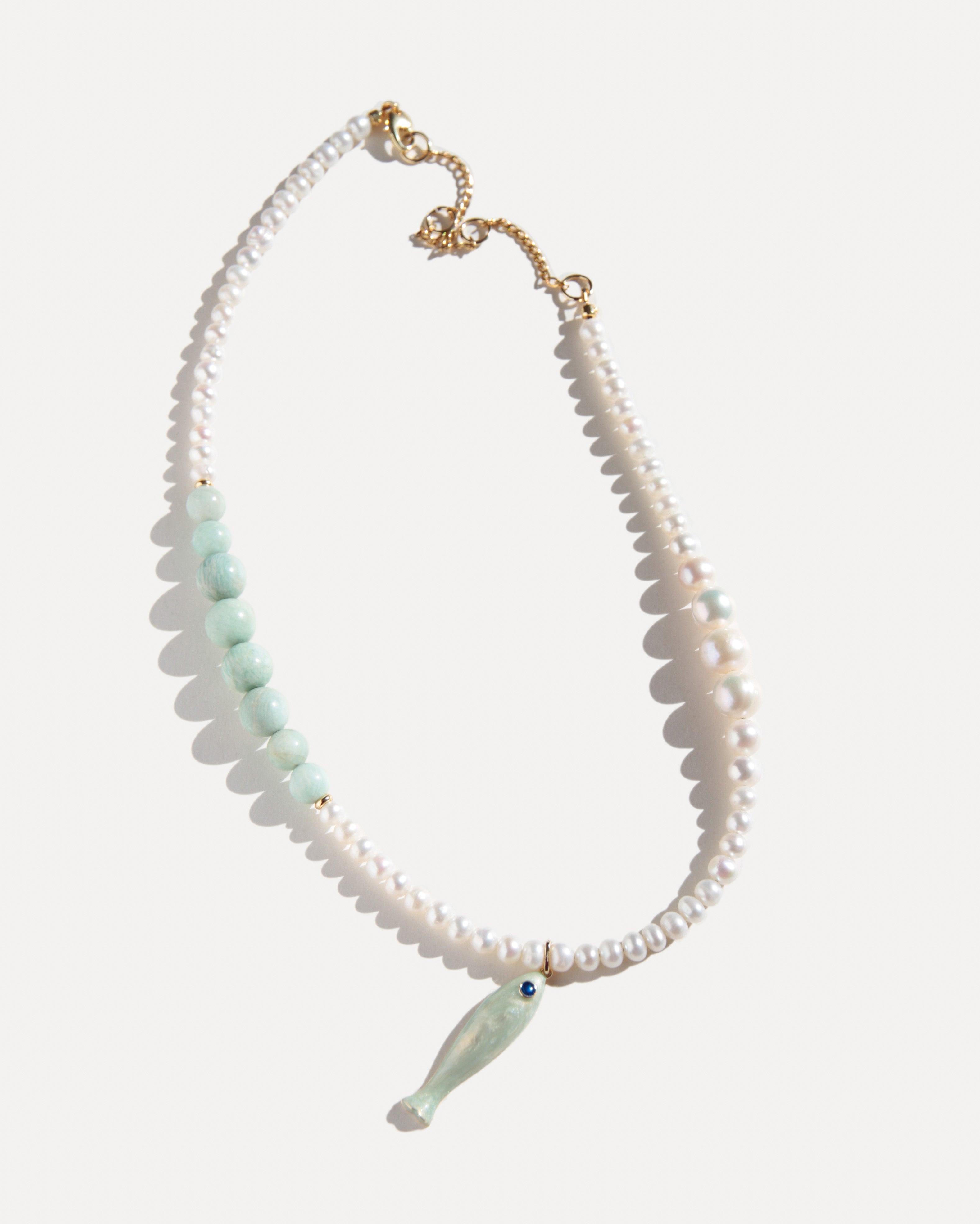 freshwater pearl necklace with pale amazonite beads, ceramic fish pendant and 18K gold-plated clasp on white background