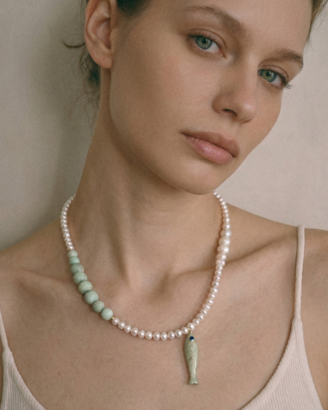 freshwater pearl necklace with pale amazonite beads, ceramic fish pendant and 18K gold-plated clasp on white background