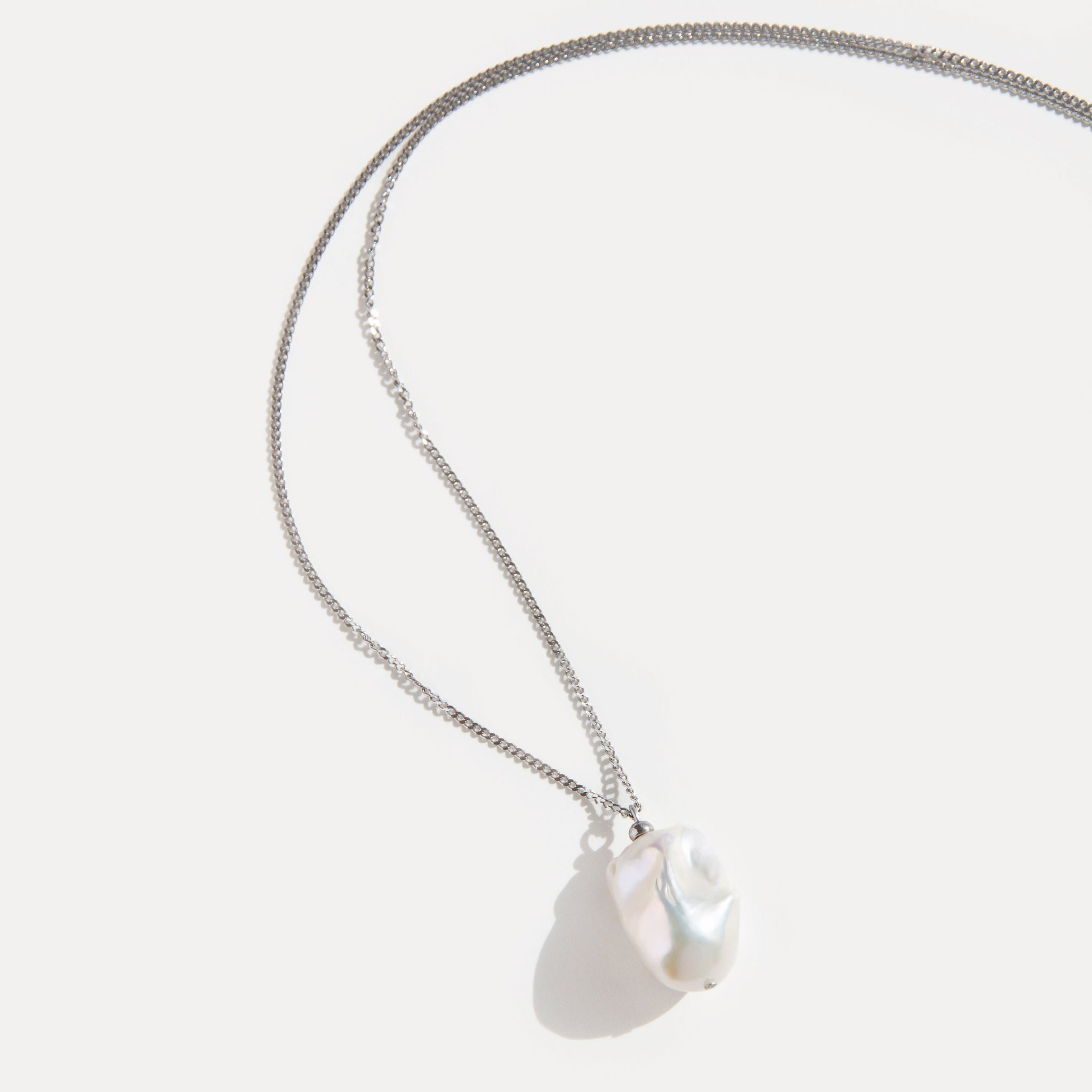 Minimalist necklace with a single baroque freshwater pearl pendant on fine stainless steel chain, elegant and timeless design.