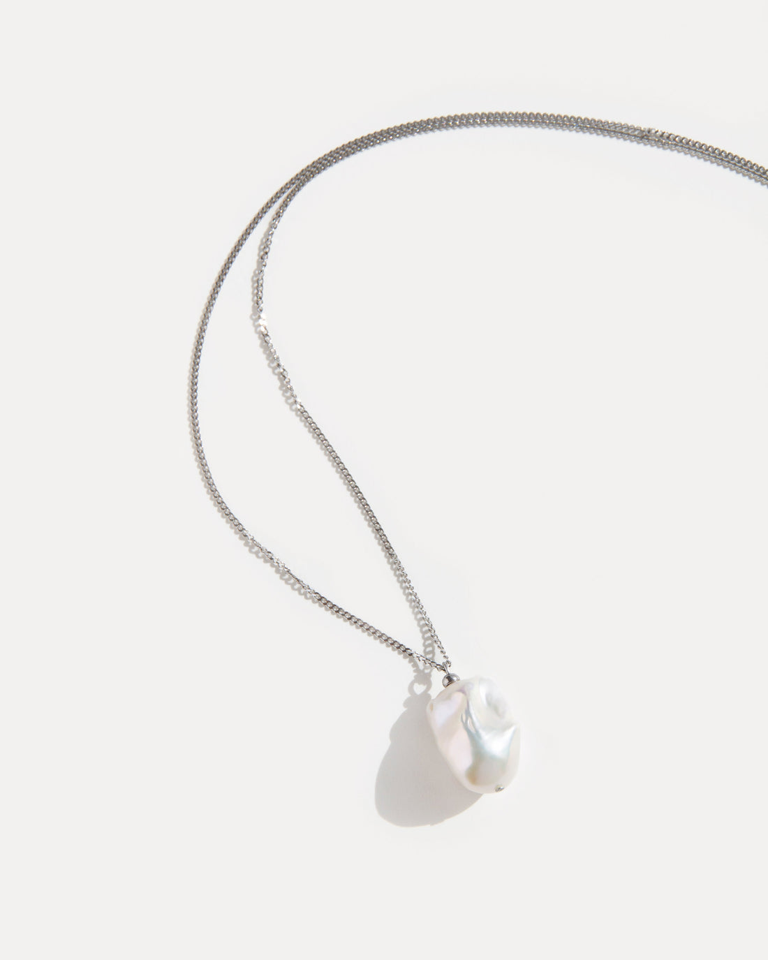 Minimalist necklace with a single baroque freshwater pearl pendant on fine stainless steel chain, elegant and timeless design.