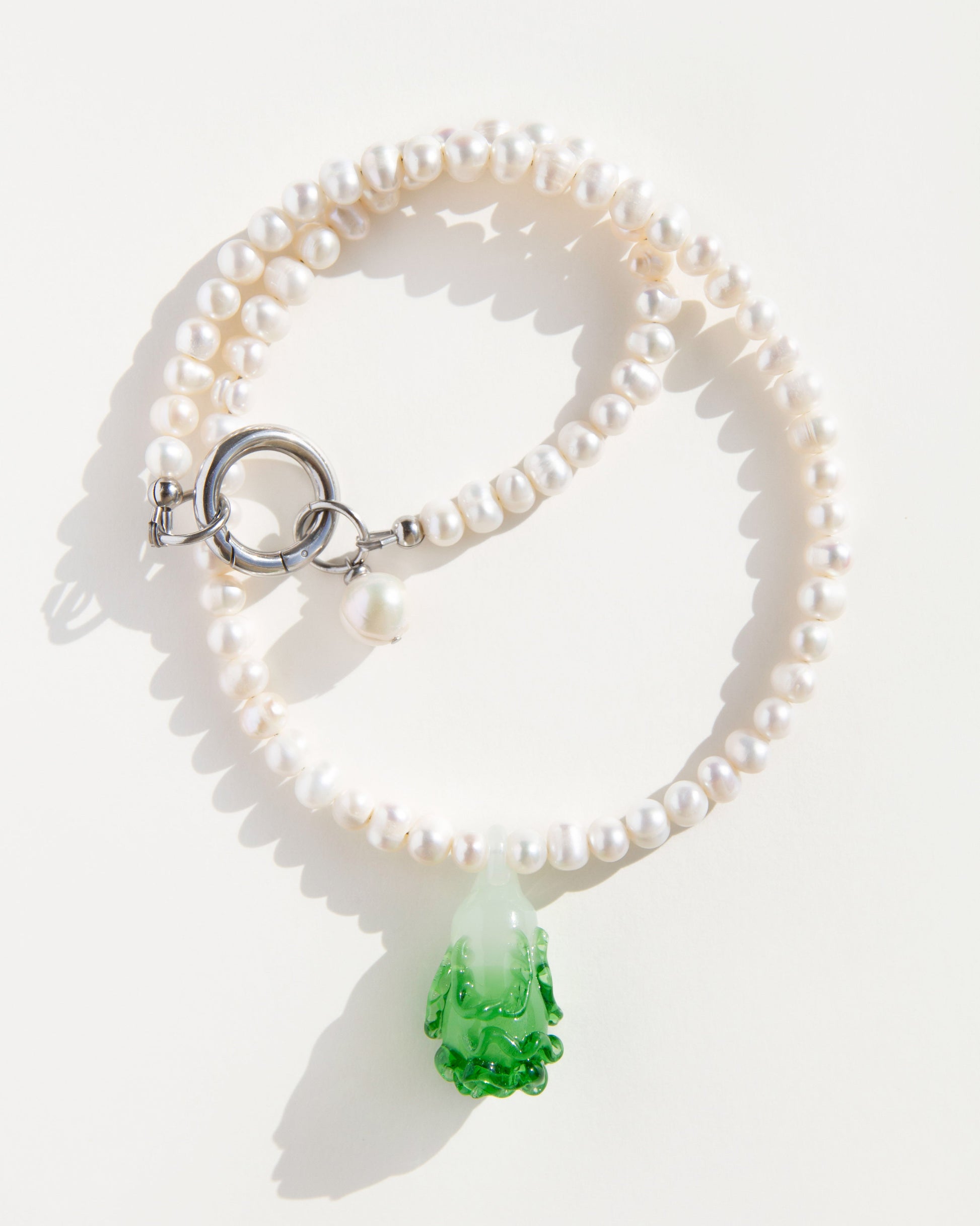 Cabbage Pearl Necklace on white background – strand of natural freshwater pearls with green lampwork glass pendant and steel clasp.