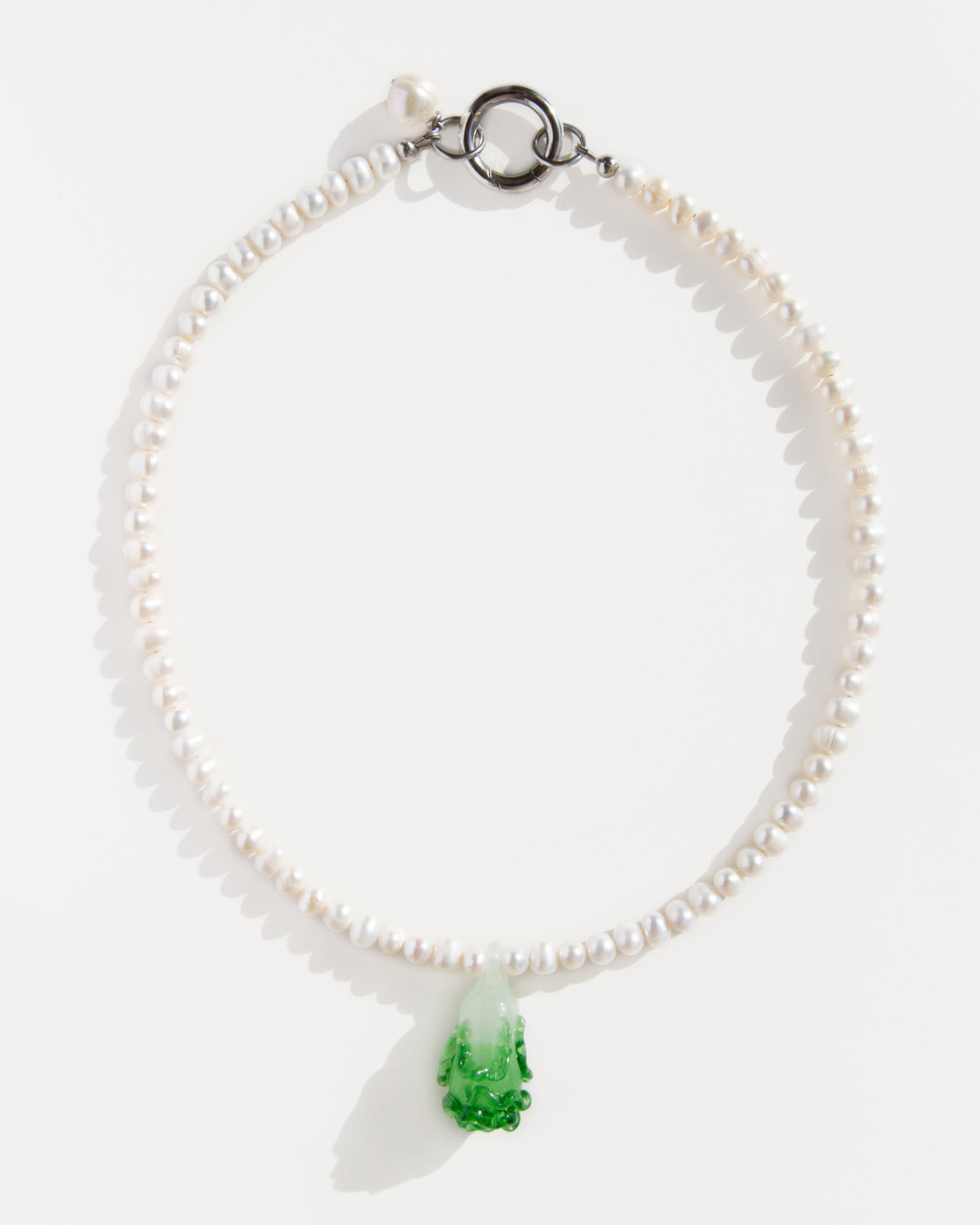 Freshwater pearl necklace with a green lampwork bok choy pendant and stainless steel clasp – minimal flat lay on white background.