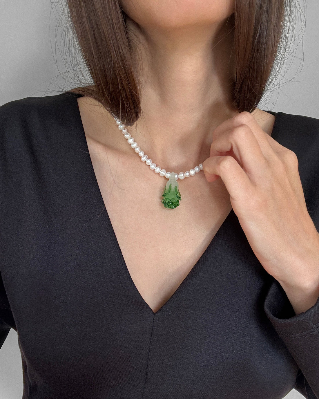 Freshwater pearl necklace with a green lampwork bok choy pendant and stainless steel clasp – minimal flat lay on white background.