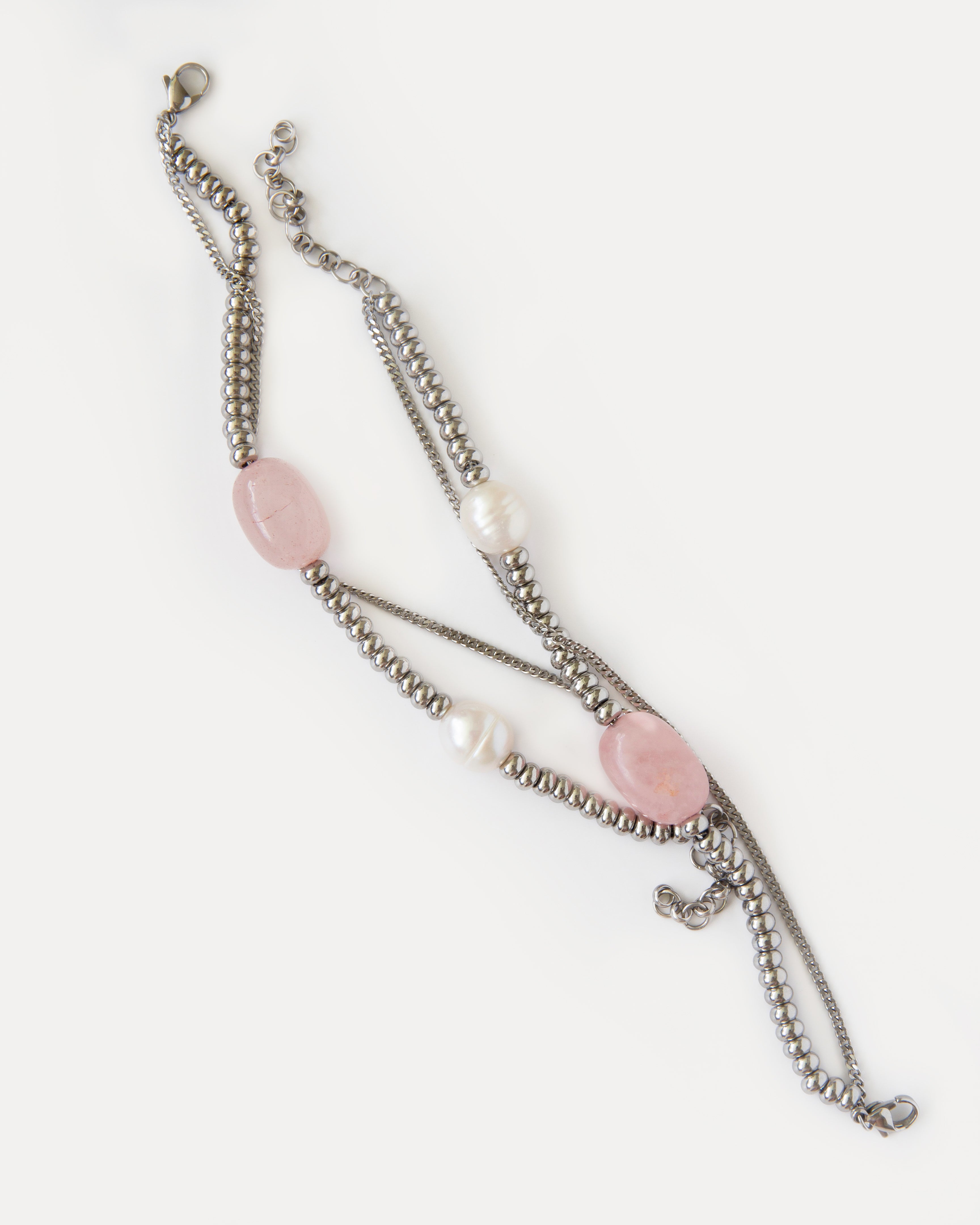 Candy Bracelet shown laid flat, highlighting its asymmetric composition with rose quartz, freshwater pearls, and polished stainless steel details.