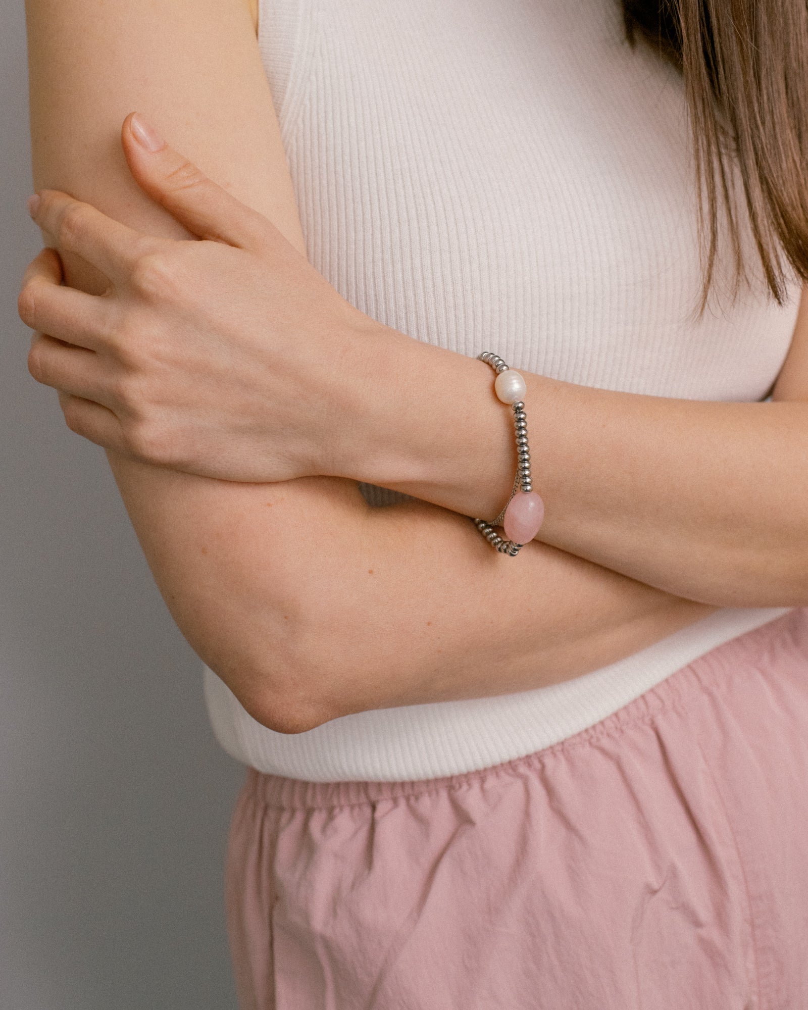 Candy Bracelet with rose quartz and pearl styled on the wrist — soft pink tones meet sleek steel for a clean, feminine and effortlessly modern look.