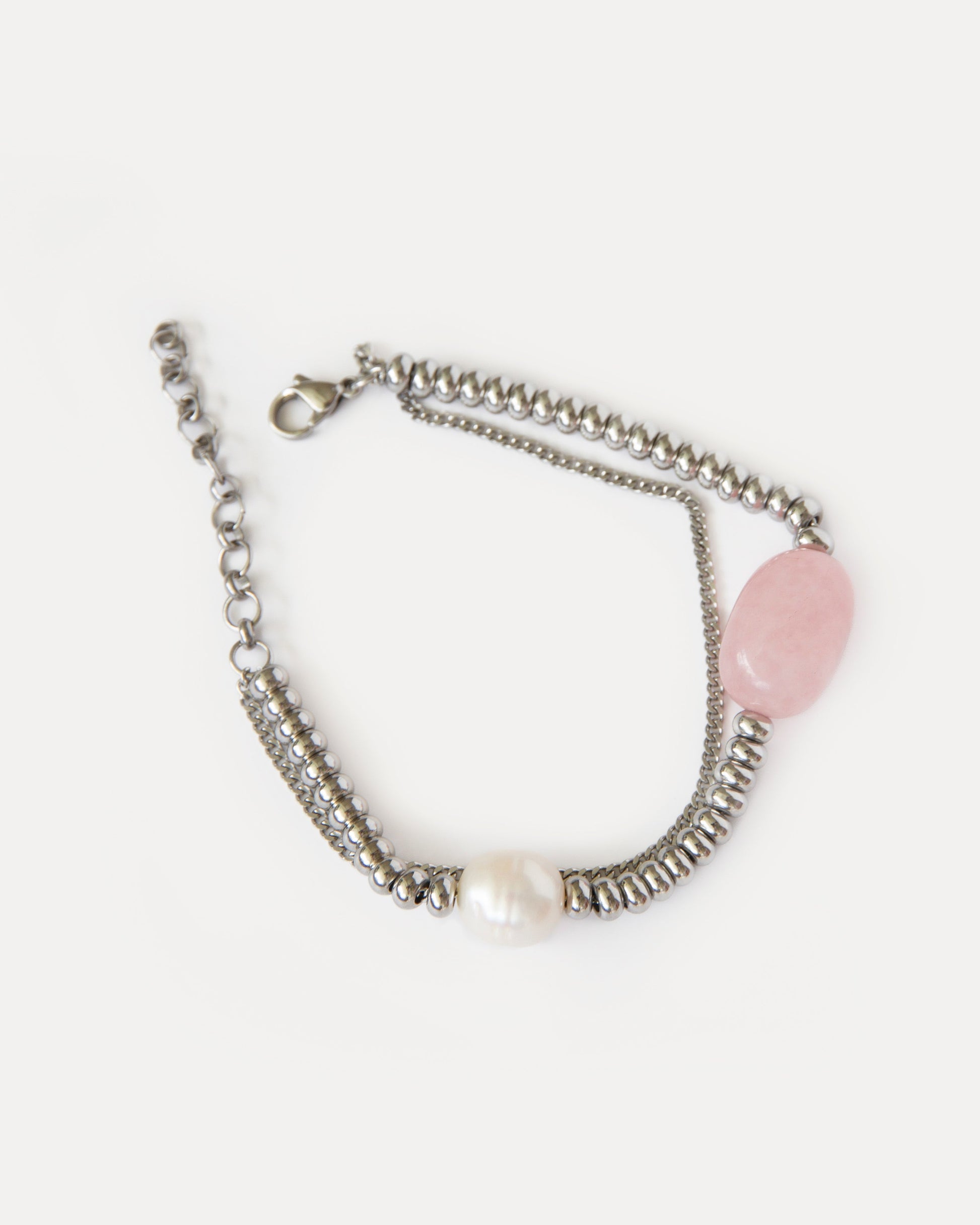 Close-up of the Candy Bracelet featuring rose quartz, freshwater pearl, and polished stainless steel — minimalist design with a soft, modern glow.
