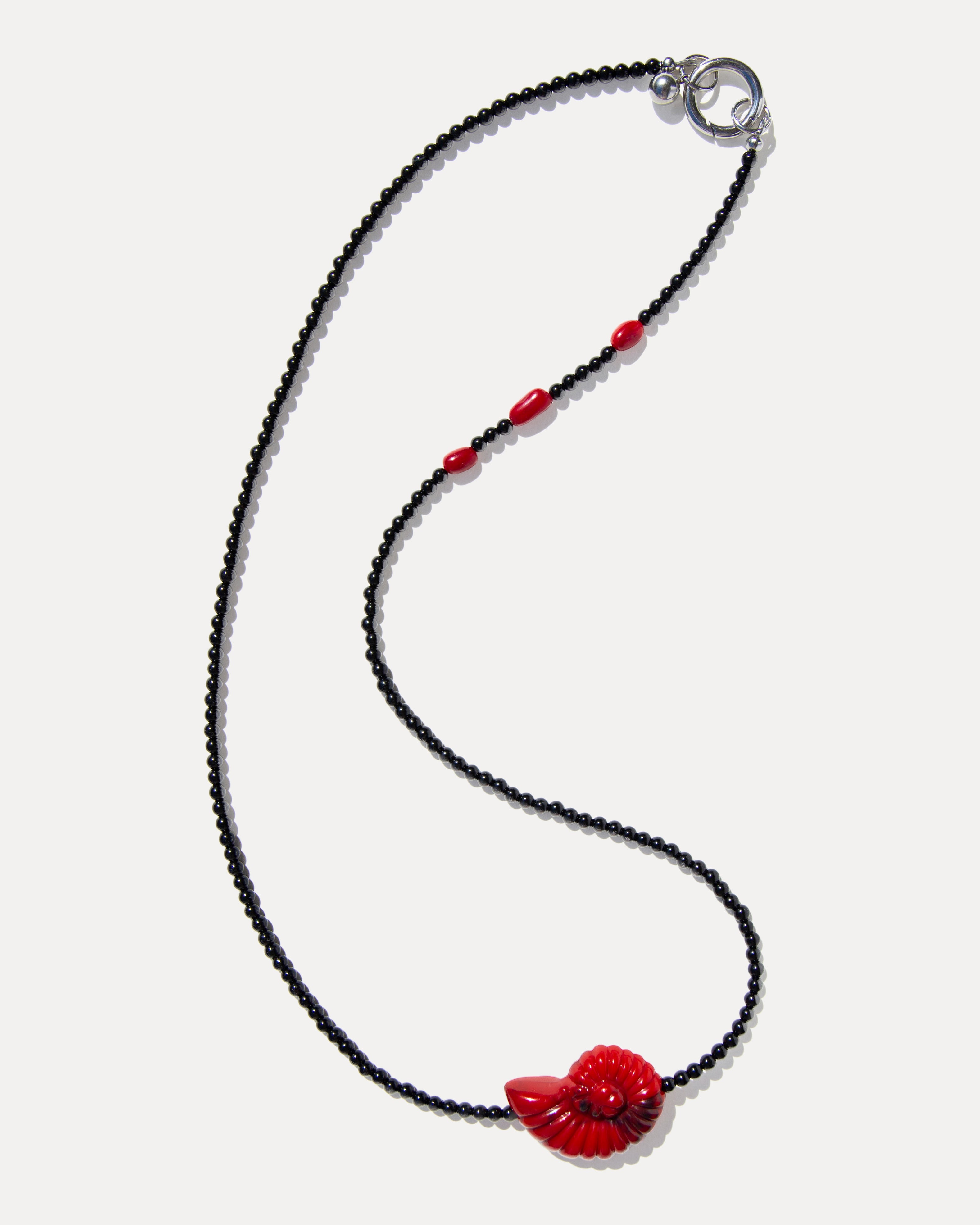 Long black agate necklace with coral beads and a red shell pendant, shown in its full-length design