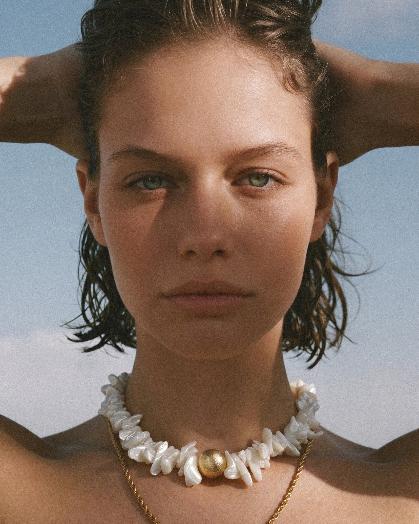 statement shell choker necklace with white shell beads and gold detail on model, styled close to the neck in warm natural light