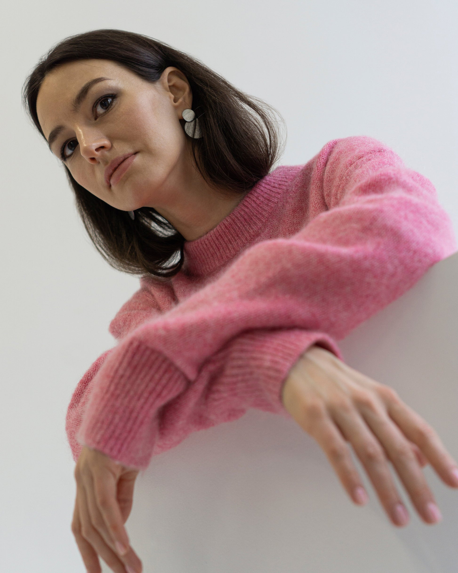 Model wearing silver double-disc statement earrings styled with a pink knit sweater. Sleek geometric design adds modern charm to minimalist everyday wear.