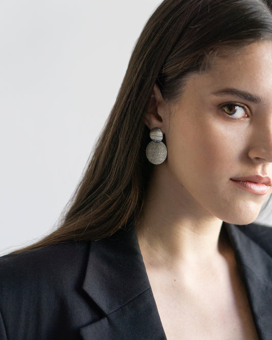 Silver statement earrings with dual textured discs shown on model. Modern geometric design adds refined edge and balance to minimalist everyday style.
