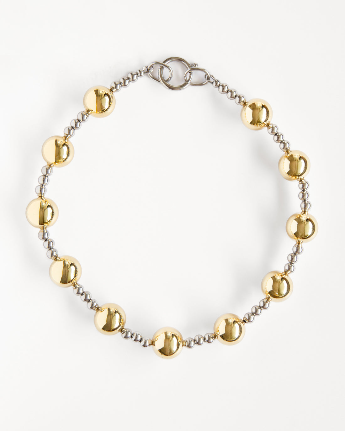 mixed metal beaded necklace with gold and silver beads arranged in a clean circular shape on white background