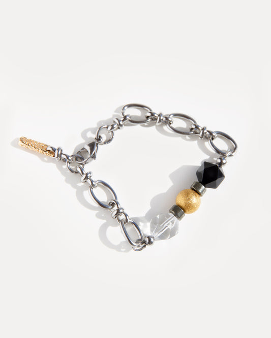 The Jazz Bracelet, laid flat and gently curved, highlighting its unique design of natural clear quartz, deep black agate, and golden 18K gold-plated brass beads, all set on a robust stainless steel chain with secure lobster clasp. This bold yet refined mixed-metal bracelet offers a versatile minimalist statement, perfect for everyday wear or creative layering. Discover Jewell Reef's unique handcrafted jewelry for women.
