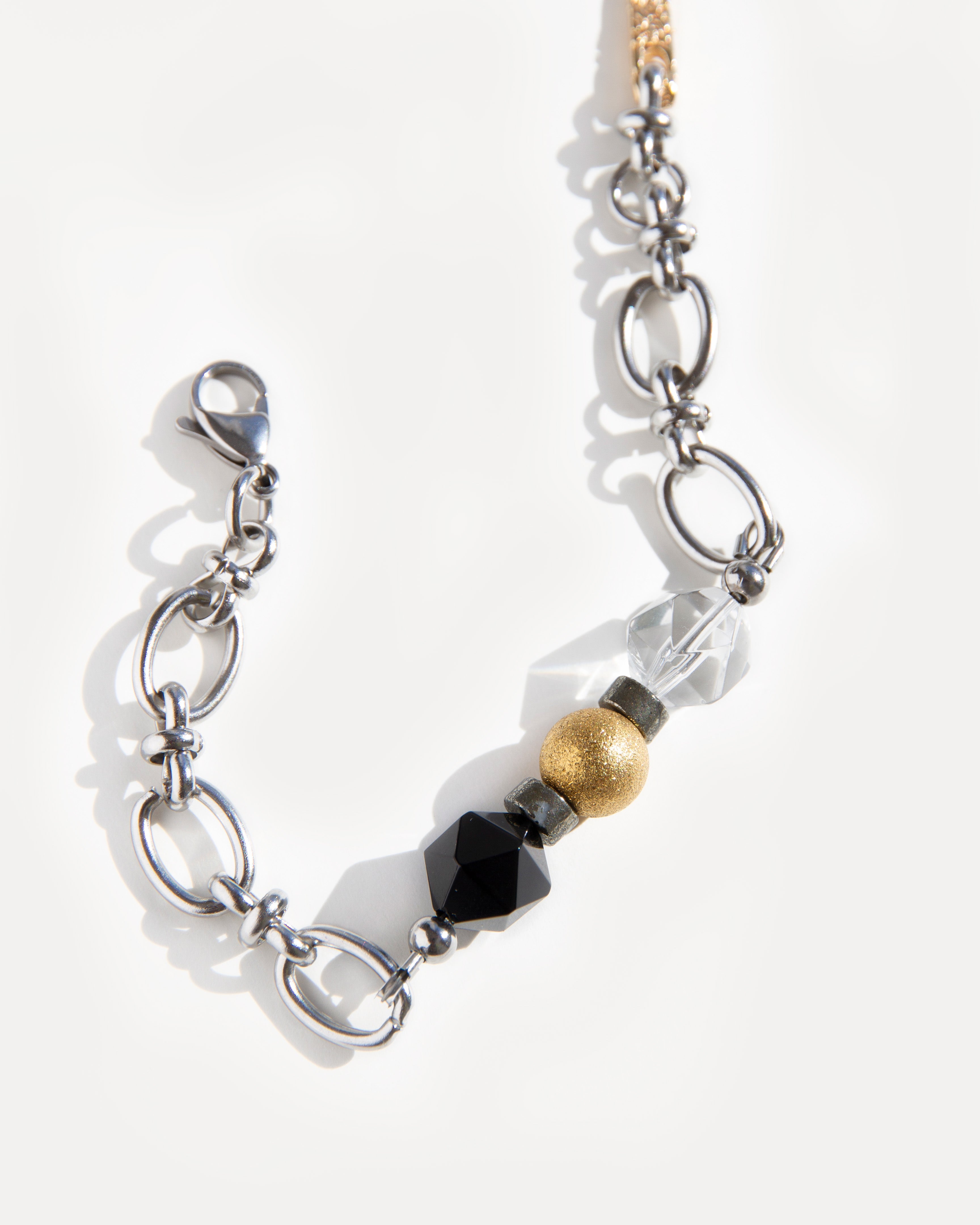 Jazz Bracelet with stainless steel chain, faceted black agate, clear quartz, hematite and 18K gold-plated bead on neutral background