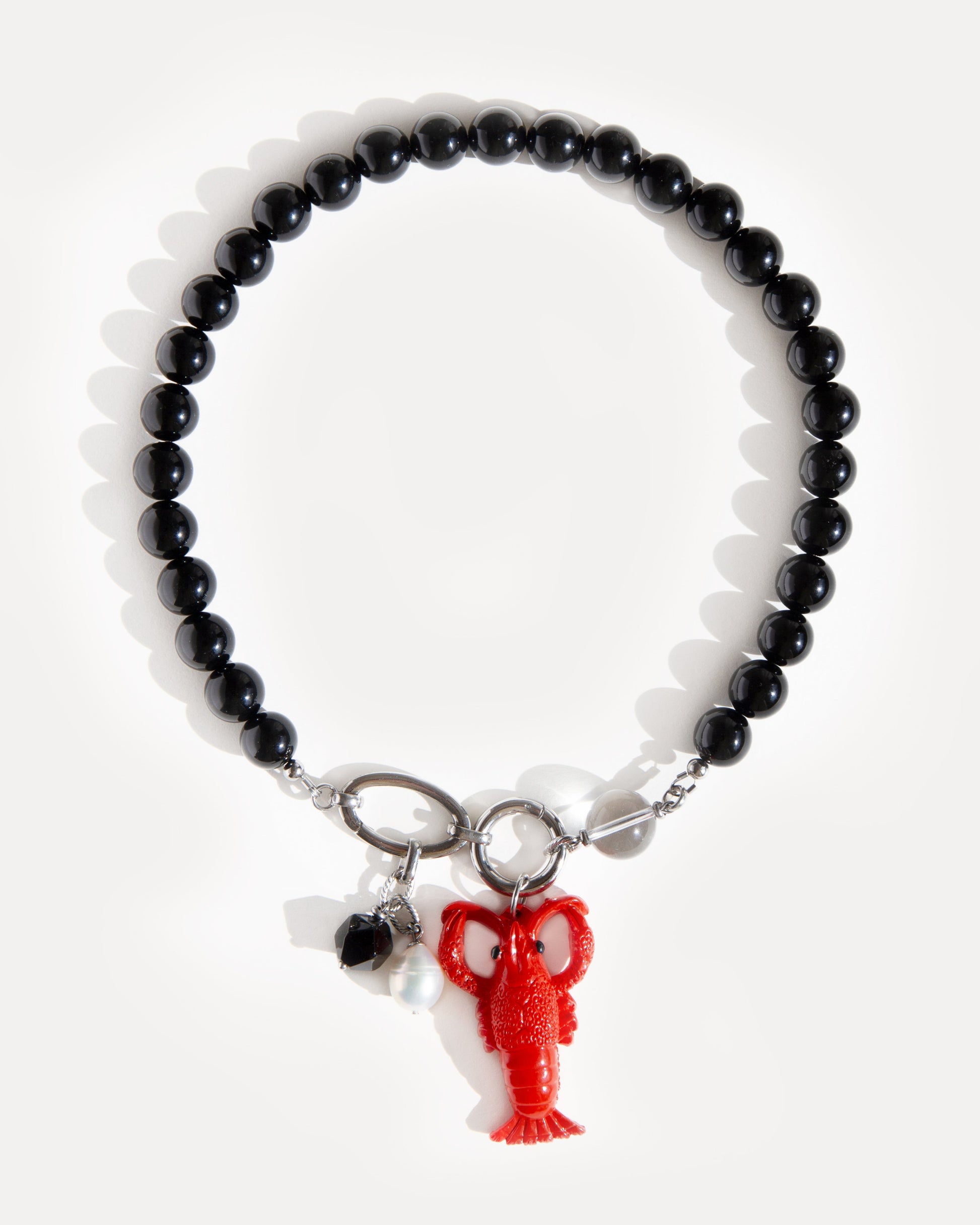 Jewell Reef Lobster Noir Necklace on white background — handcrafted black agate bead necklace with stainless steel details and detachable pendants. Shown with the bold red lobster charm, faceted black agate, and freshwater pearl. A versatile statement necklace inspired by the ocean, perfect for artistic everyday wear or striking evening looks. Unique lobster pendant necklace for modern minimalism with a twist.
