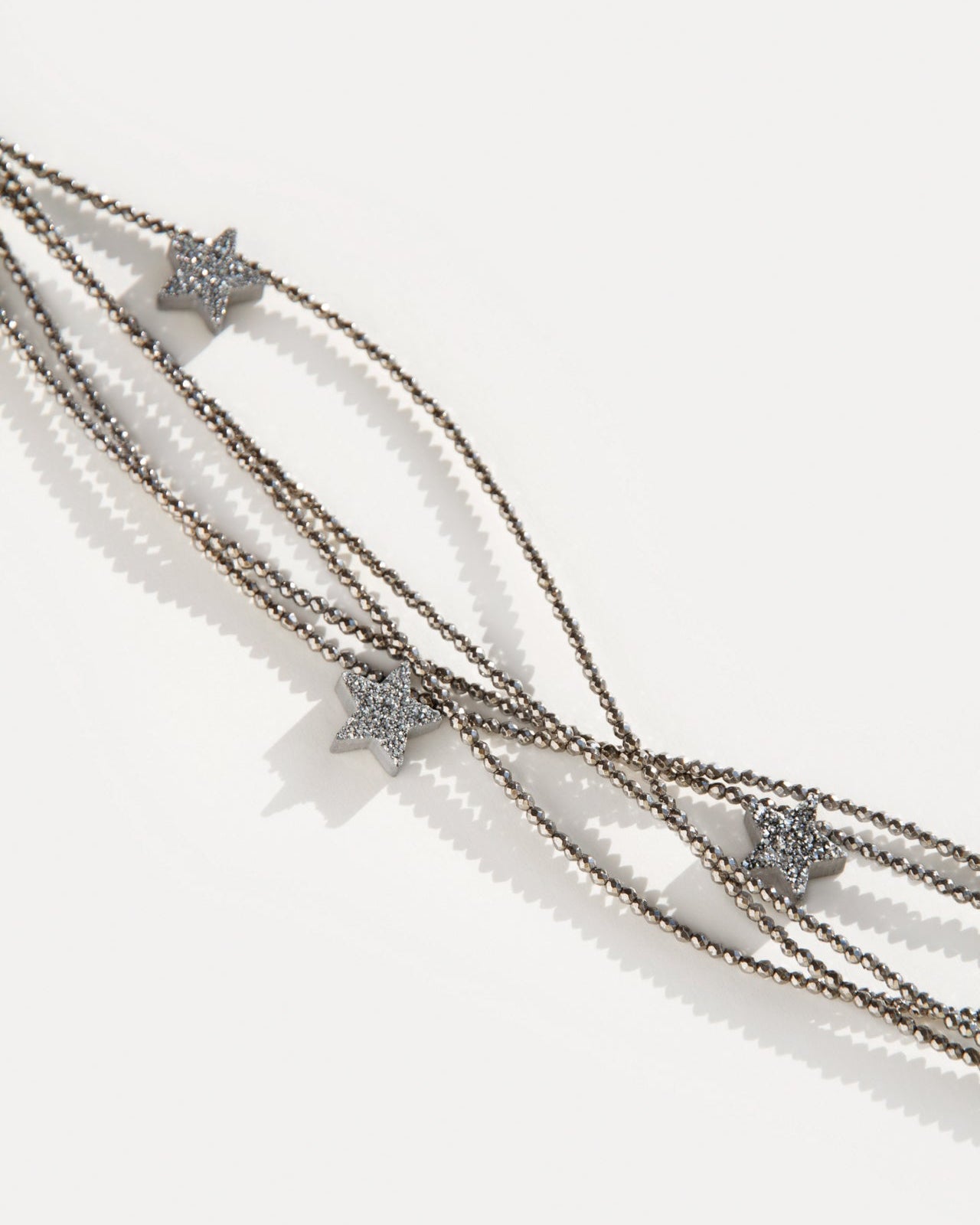 Close-up of Make a Wish Necklace with shimmering hematite strands and druzy agate star charms. Layered statement necklace with celestial-inspired detail.