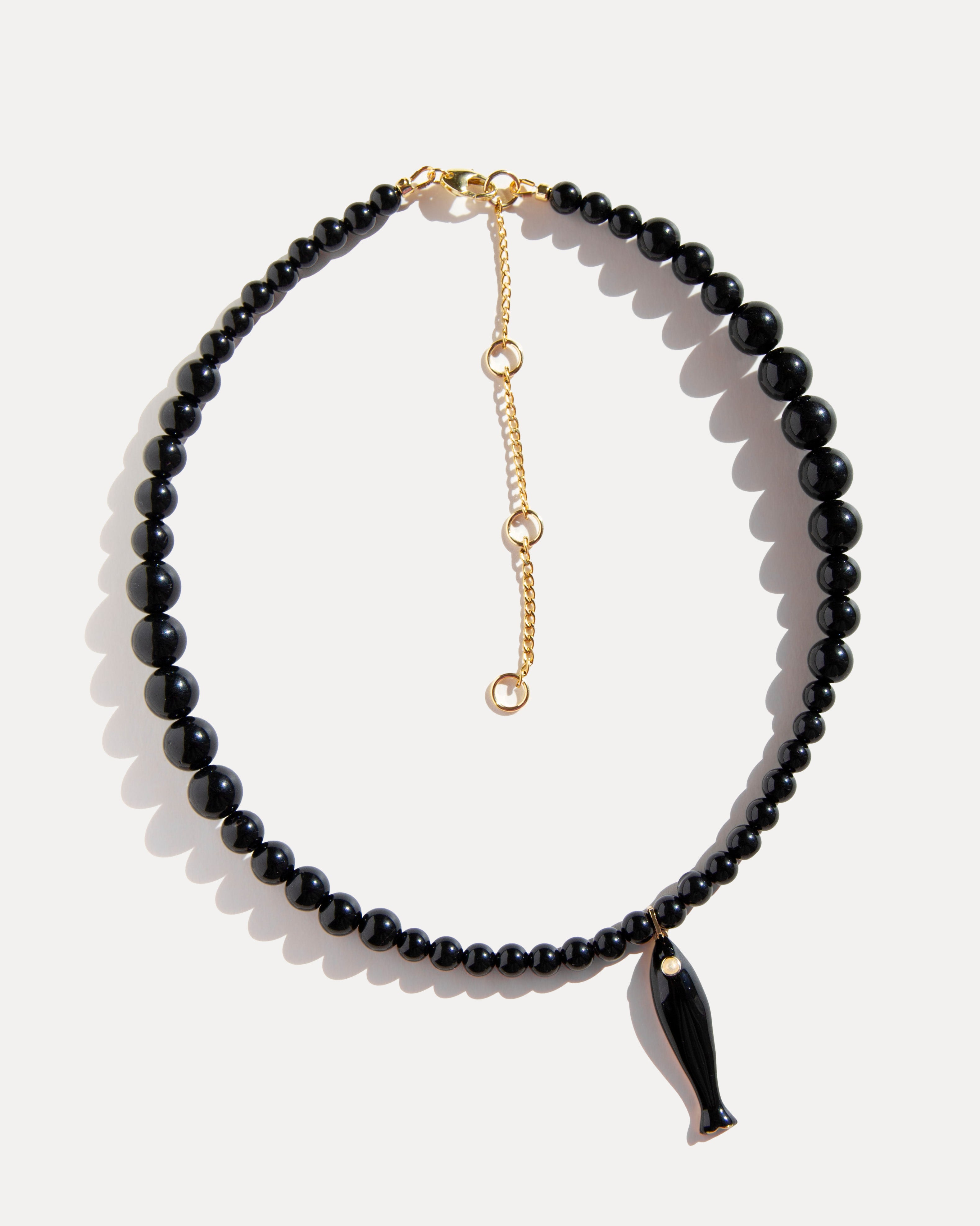 Black agate necklace with ceramic fish pendant and gold-plated clasp photographed on white background