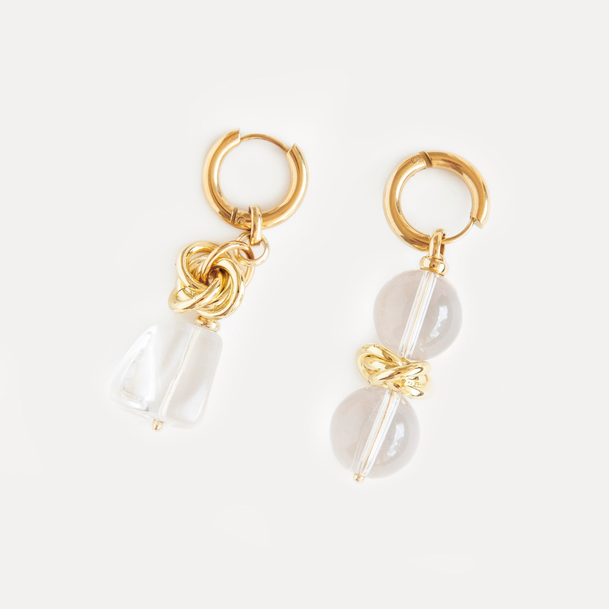Asymmetric gold-plated hoop earrings with clear quartz drops. Bold sculptural statement design blending modern minimalism and organic charm.