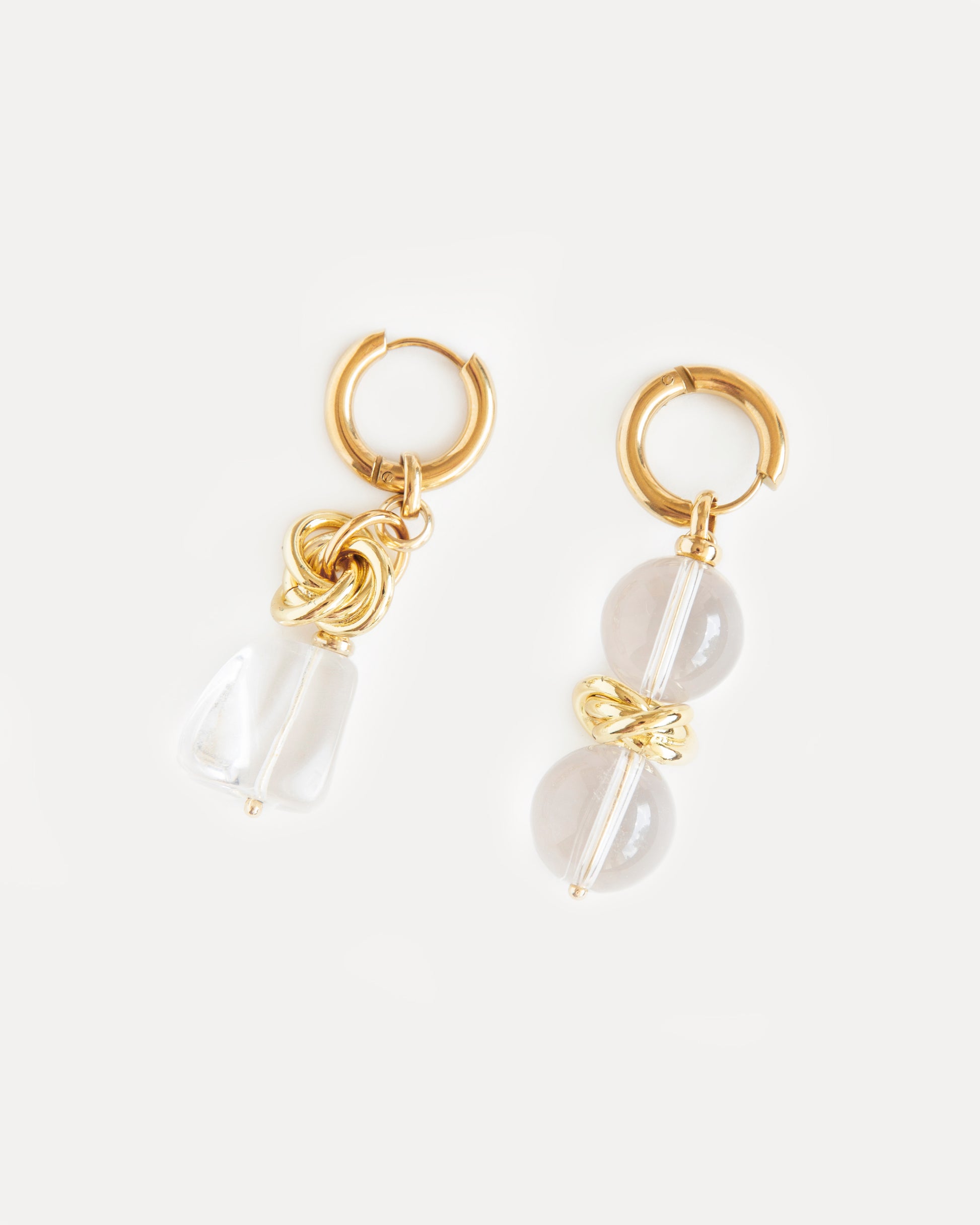 Asymmetric gold-plated hoop earrings with clear quartz drops. Bold sculptural statement design blending modern minimalism and organic charm.