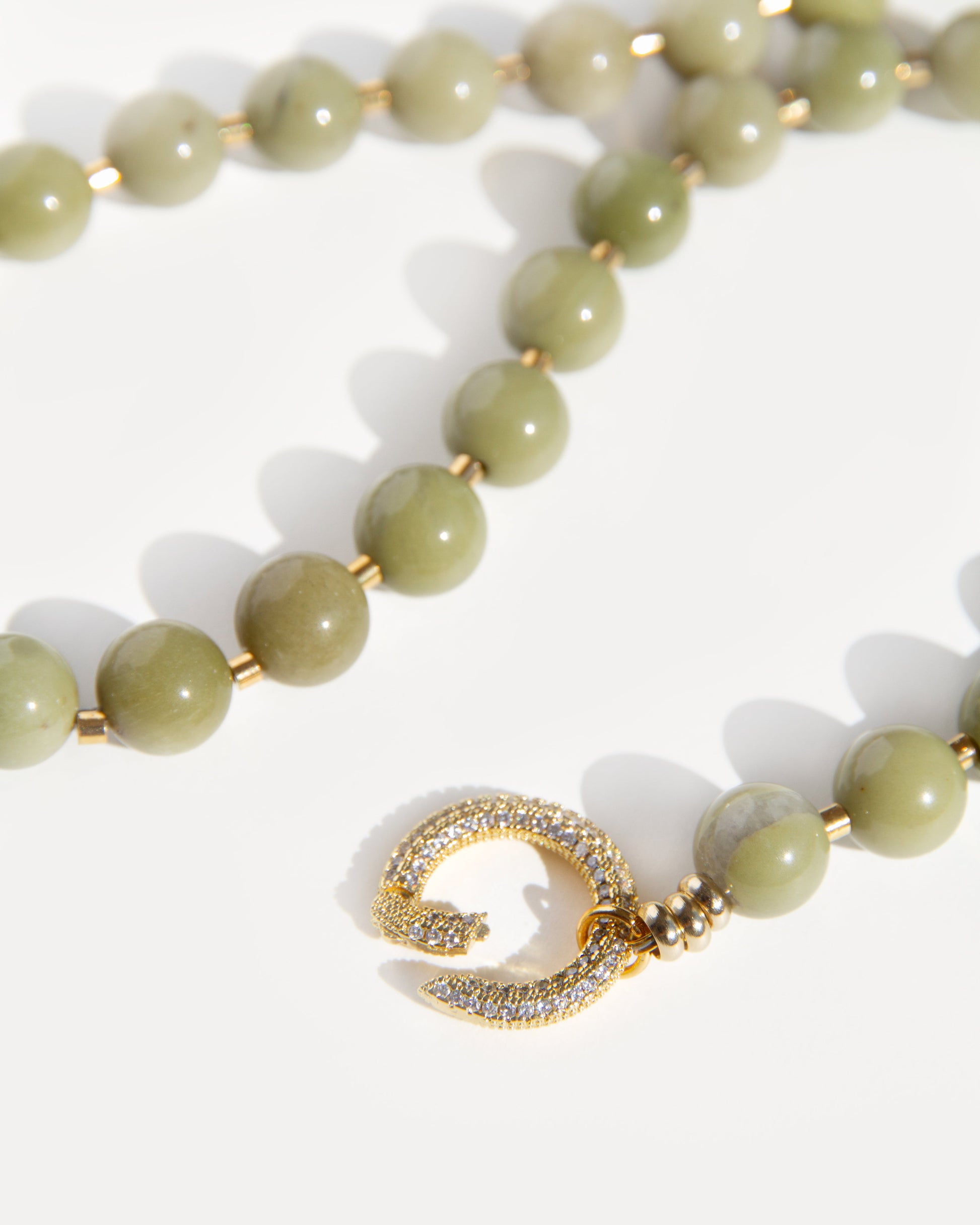 Detailed close-up of Olivia Necklace clasp with cubic zirconia set in gold-plated brass, paired with polished olive-green agate beads.