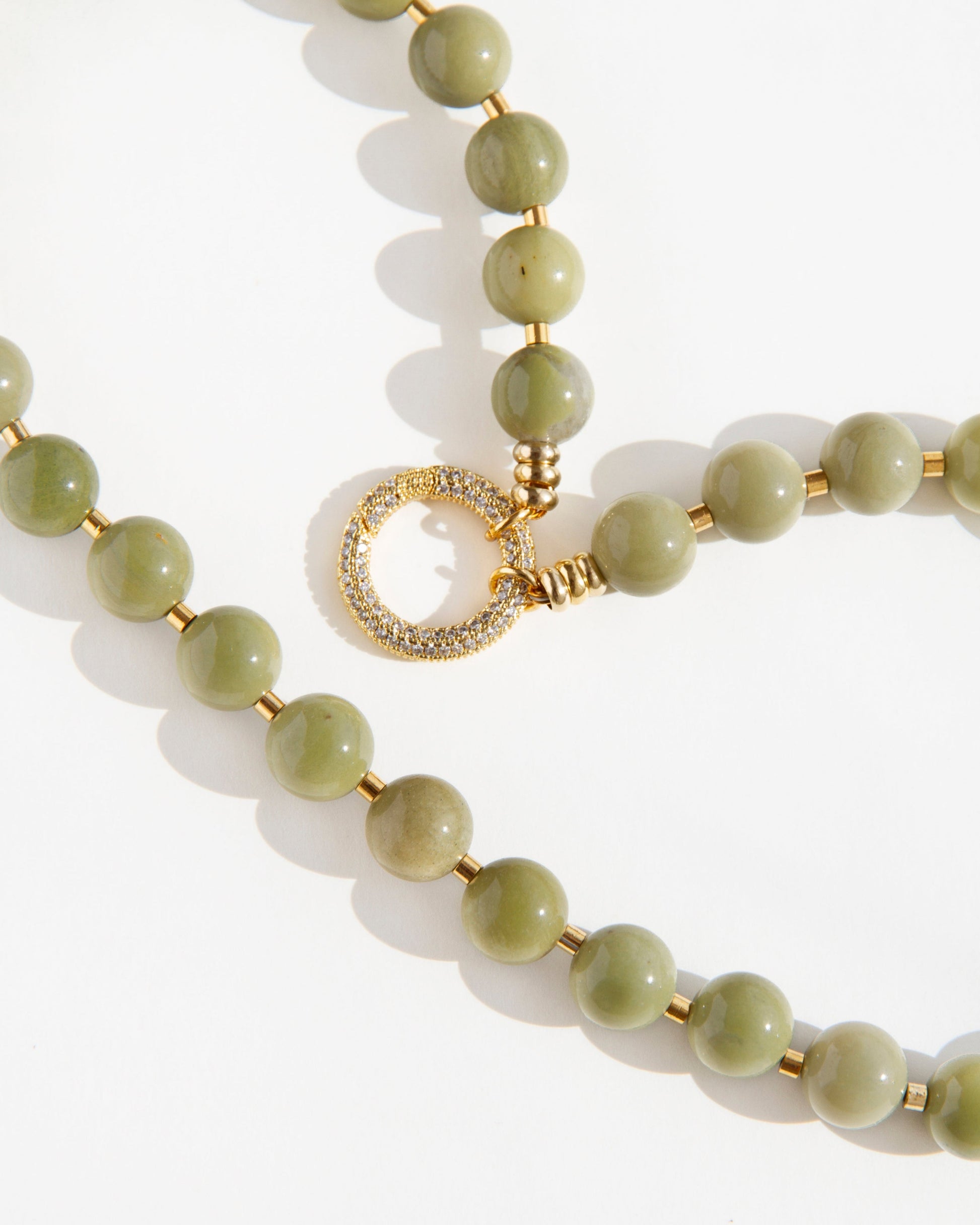 Close-up of Olivia Necklace with polished olive-green agate beads, gold-plated accents, and cubic zirconia clasp detail on a white background.