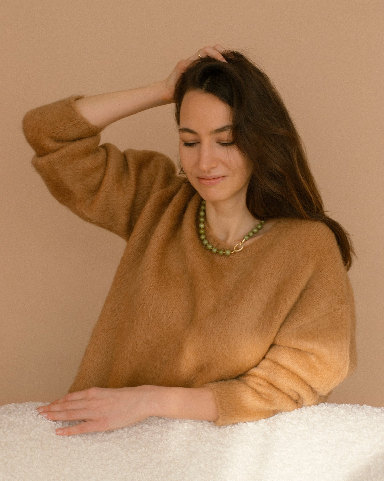 Model wearing Olivia Necklace with olive-green agate beads and cubic zirconia gold clasp, styled with a soft beige sweater for an elegant everyday look.