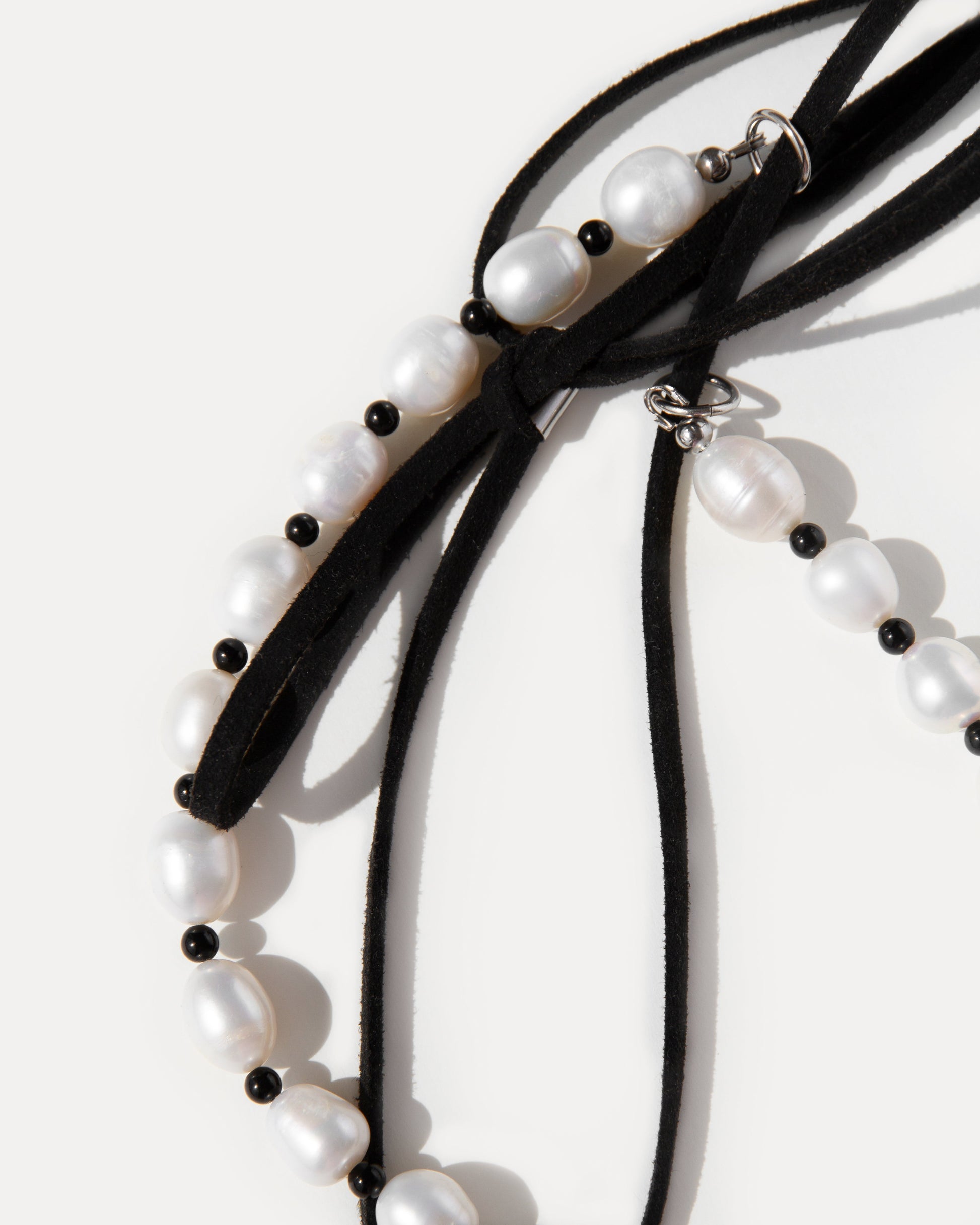 Close-up of Pearl Mademoiselle Necklace with freshwater pearls, black agate and adjustable suede cord tied into a bow.