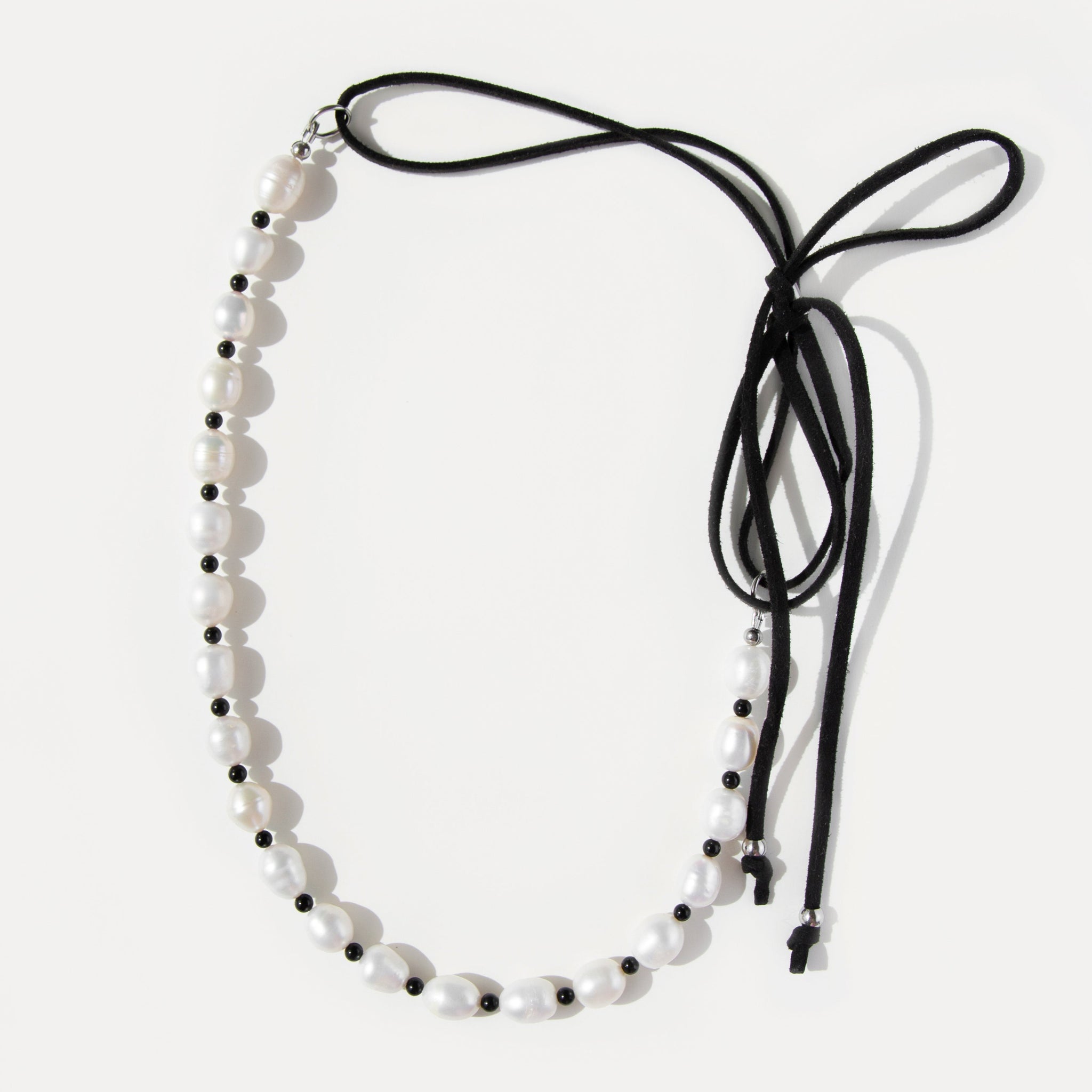 Pearl Mademoiselle Necklace with freshwater pearls, black agate beads, and an adjustable suede cord that ties into a playful bow.