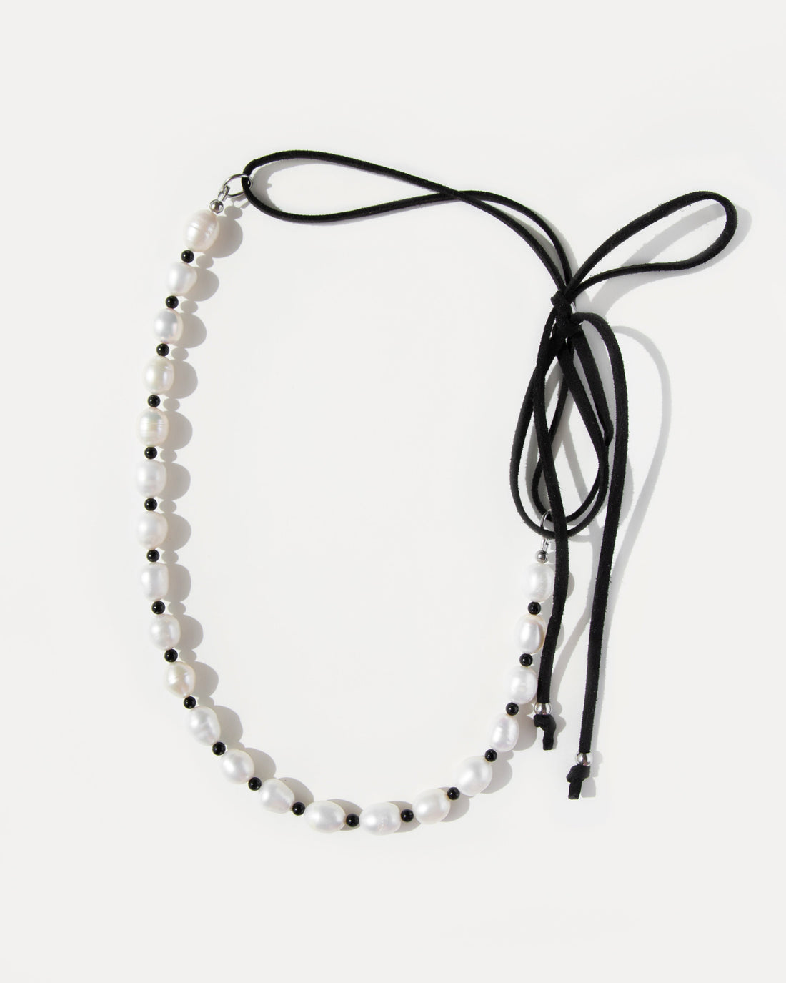 Pearl Mademoiselle Necklace with freshwater pearls, black agate beads, and an adjustable suede cord that ties into a playful bow.