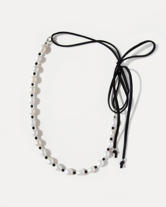 Pearl Mademoiselle Necklace with freshwater pearls, black agate beads, and an adjustable suede cord that ties into a playful bow.