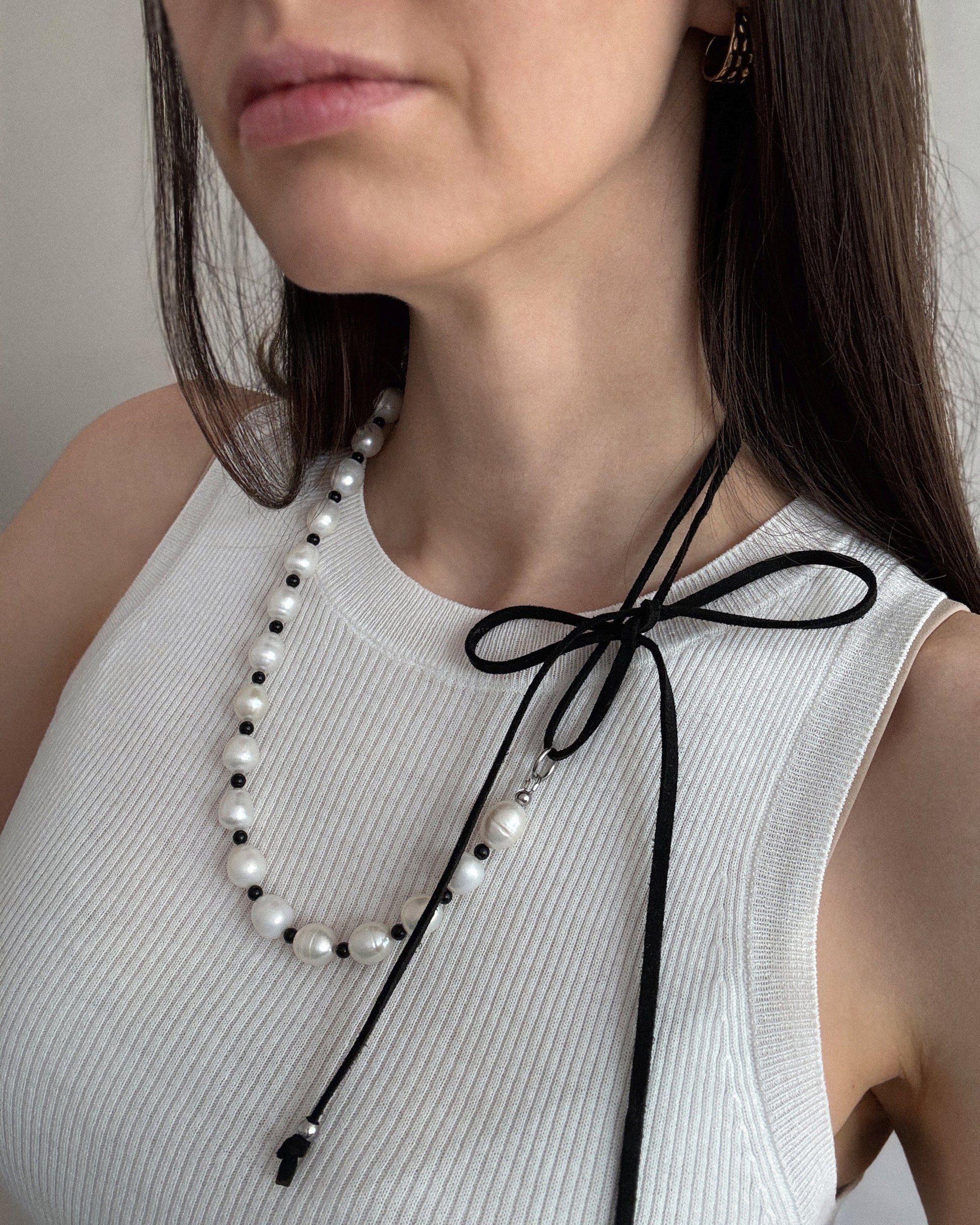 Pearl Mademoiselle Necklace styled as a chic bow-tied choker with freshwater pearls and black agate on suede cord.