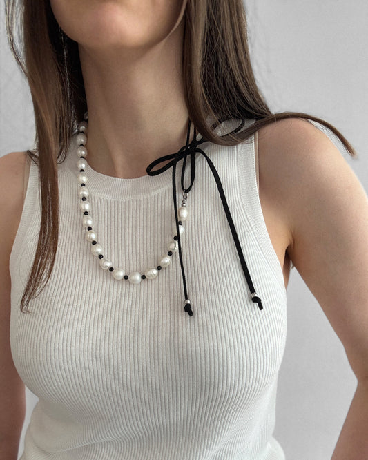 Pearl Mademoiselle Necklace with freshwater pearls, black agate, and a suede tie worn long for an elegant, feminine look.