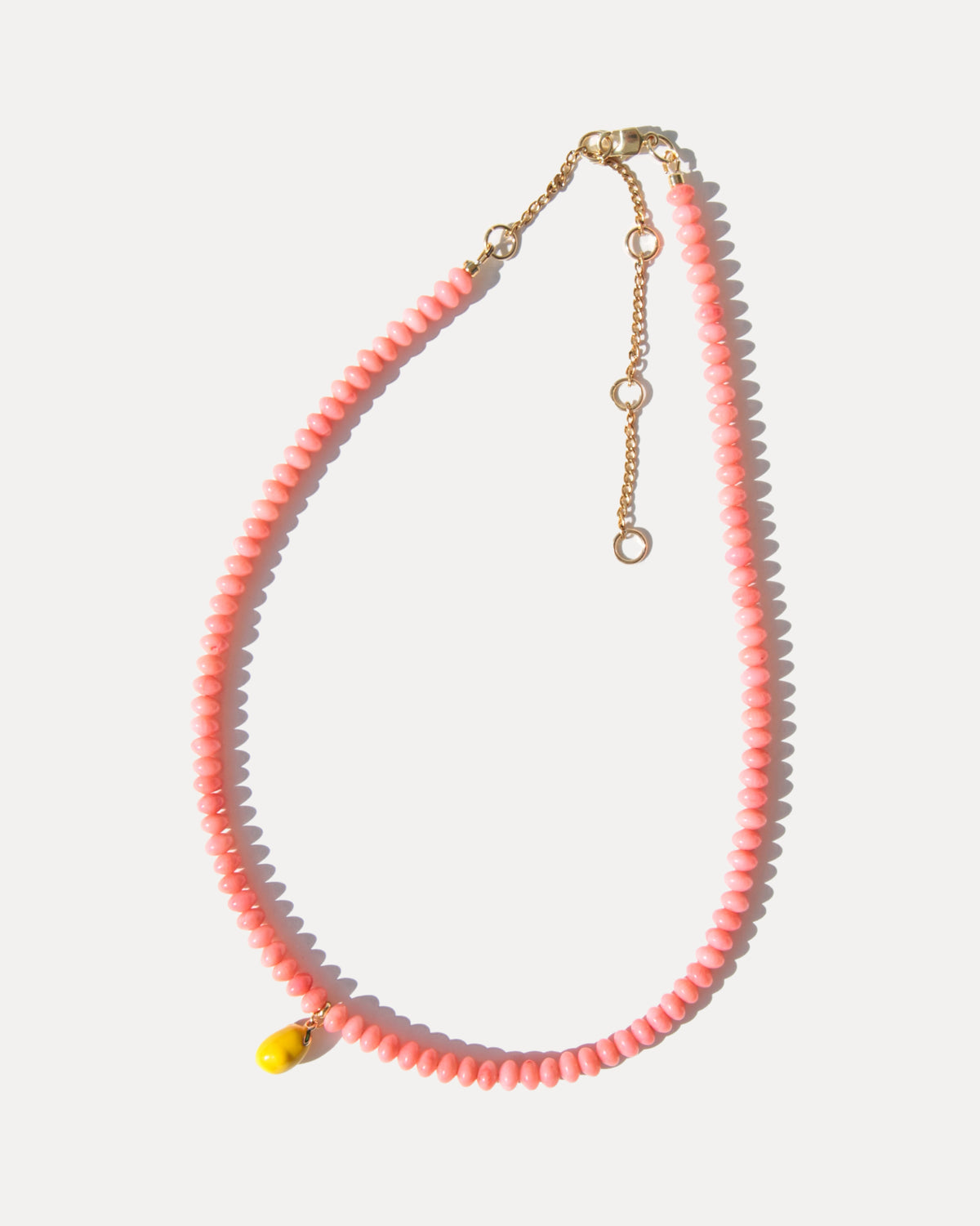 Adjustable pink coral necklace with enamel lemon charm and gold-plated extender chain, shown laid flat.