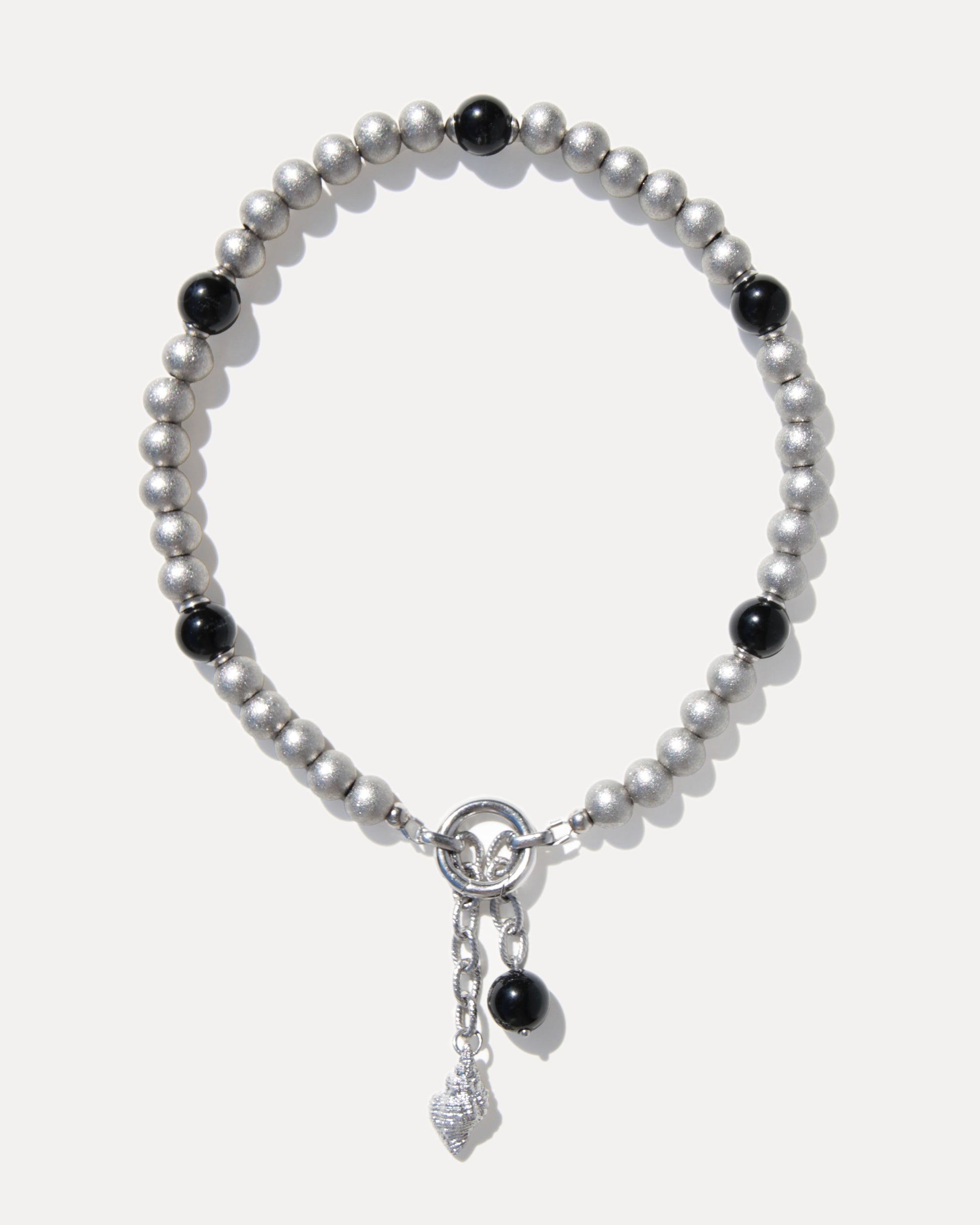 Silver-toned pearl necklace with black agate beads, stainless steel clasp and sculptural shell pendant on a clean white background.
