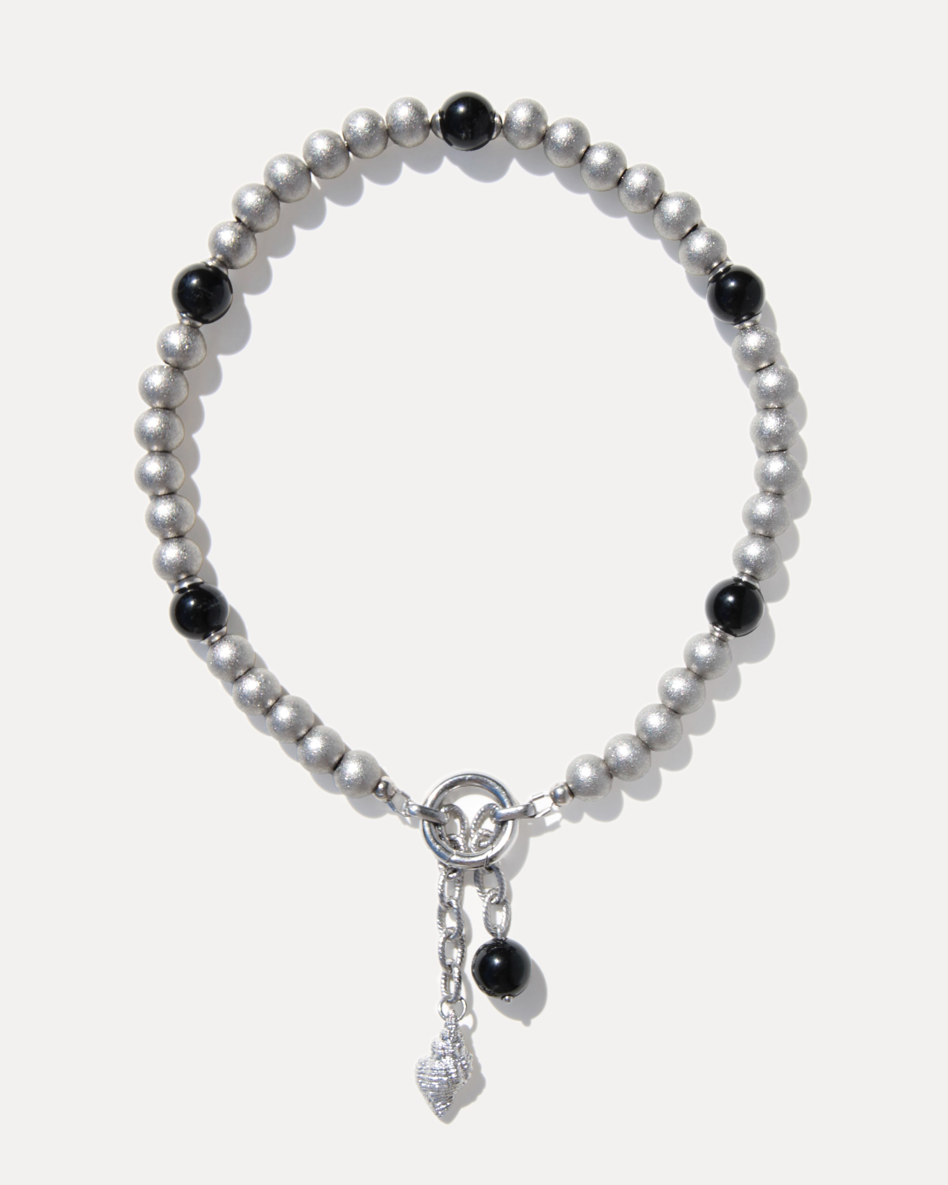 Silver-toned pearl necklace with black agate beads, stainless steel clasp and sculptural shell pendant on a clean white background.