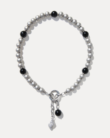 Silver-toned pearl necklace with black agate beads, stainless steel clasp and sculptural shell pendant on a clean white background.