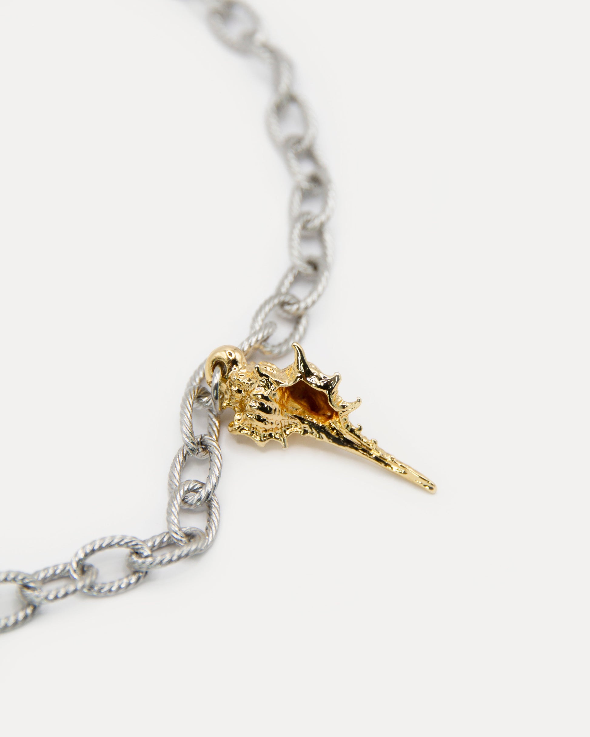 Close-up of Sea Gifts Necklace showing gold-plated sea shell charm on silver chain. Mixed metal detail highlights marine-inspired statement jewelry.