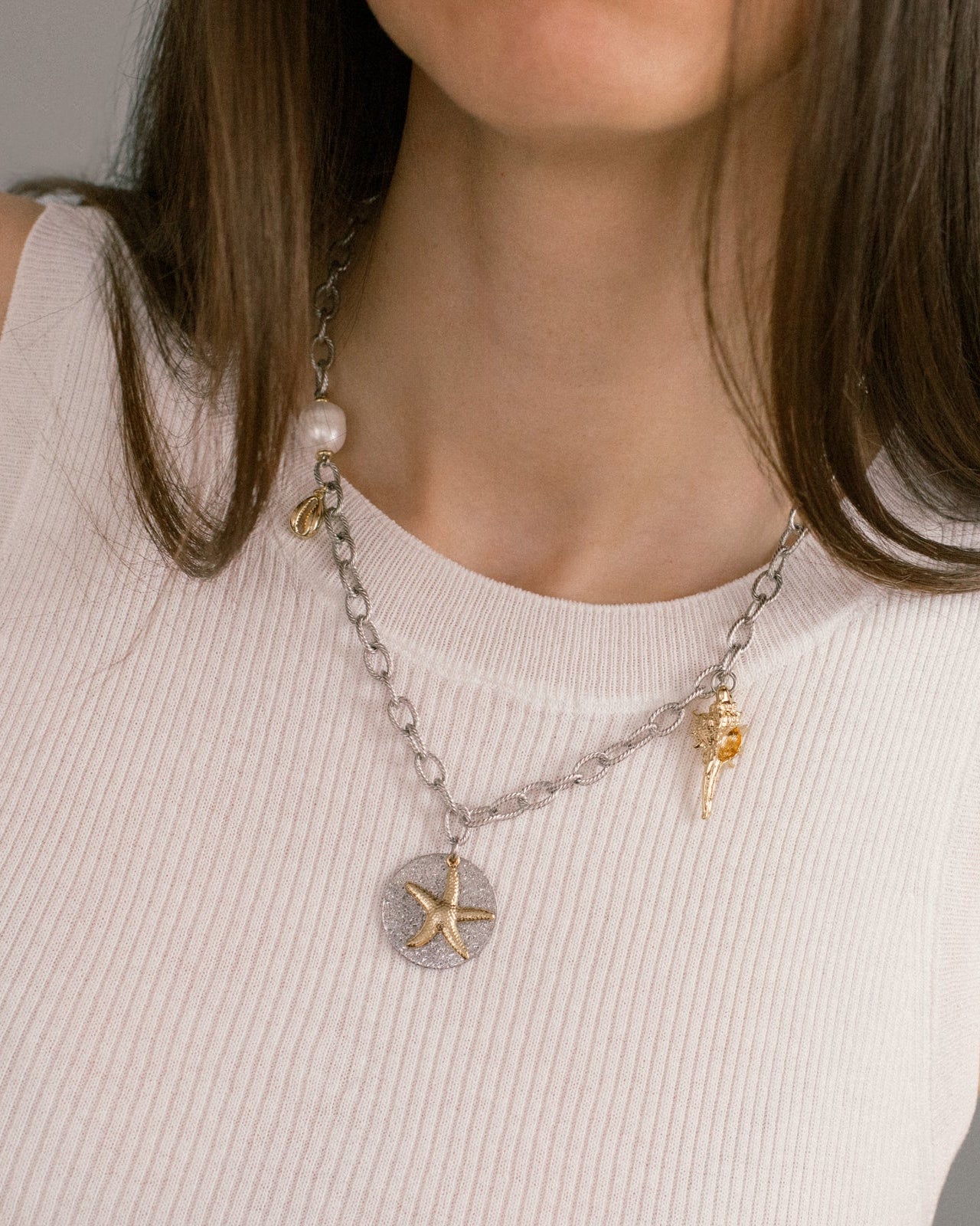 Sea Gifts Necklace styled on model — bold silver chain with starfish, shell and pearl charms. A modern mixed metal statement necklace for layering or solo wear.