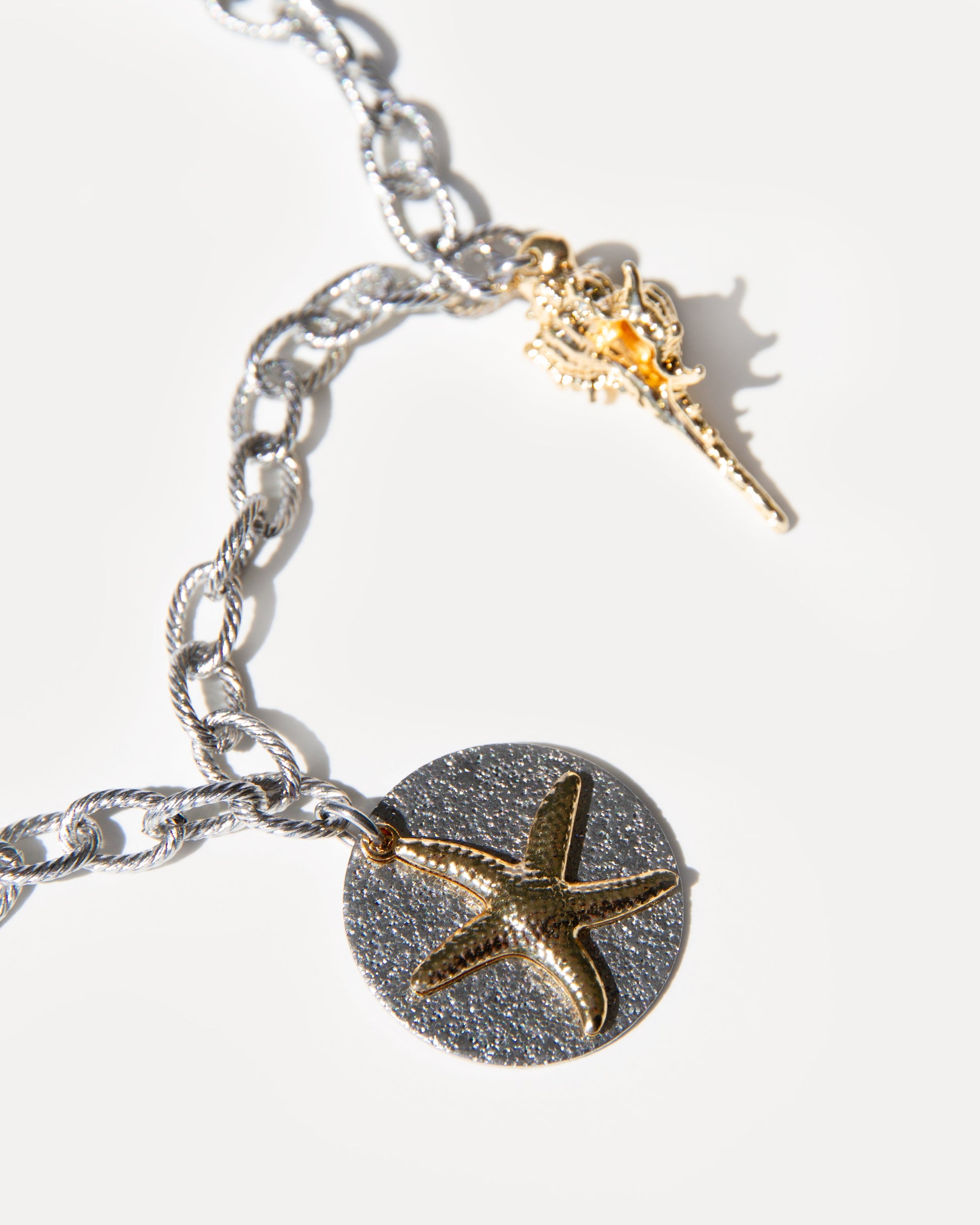 Sea Gifts Necklace close-up with silver chain, gold-plated starfish pendant and spiked shell charm. A mixed metal coastal necklace with timeless elegance.