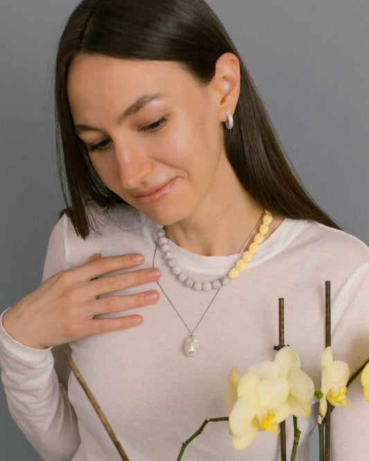 Model wearing Soft Bloom Necklace with lace agate and yellow beads, styled with baroque pearl pendant for fresh layered summer jewelry look.