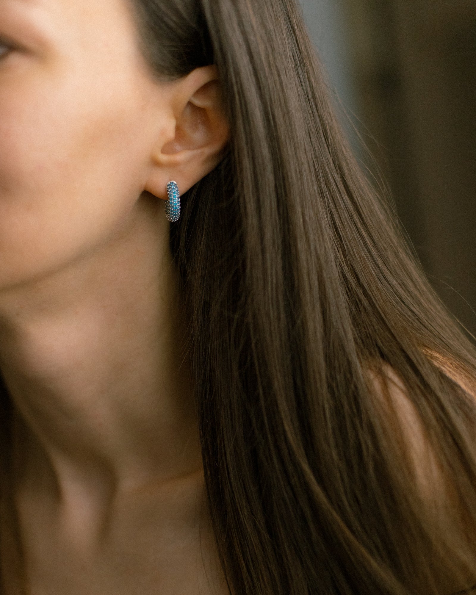 Blue cubic zirconia hoop earrings on model. Elegant mini hoops in silver-tone brass add modern sparkle and effortless shine to any look.