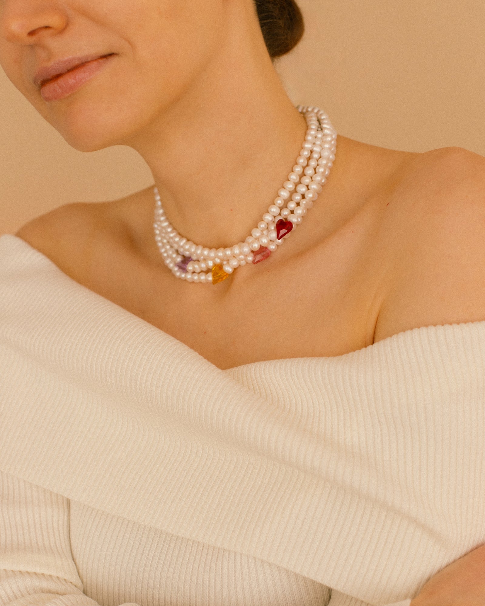 Sweetheart pearl choker necklace shown with all crystal heart colors — red, pink, purple and yellow — styled as a layered statement look.