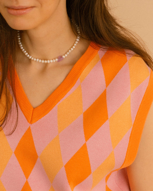 Sweetheart pearl choker necklace with natural pearls and a purple crystal heart, styled on model with colorful knit top.