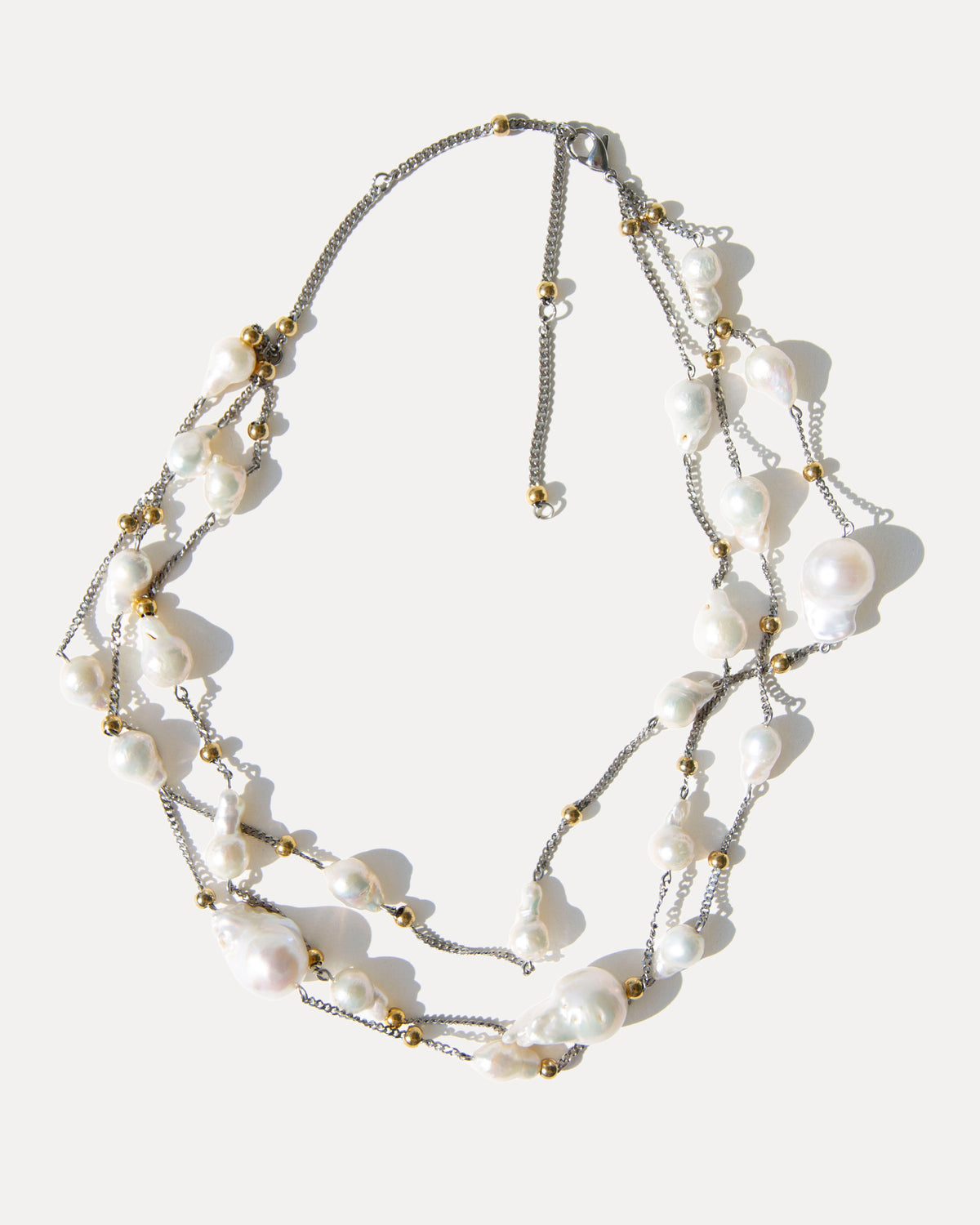 Adjustable three-strand baroque pearl necklace with irregular freshwater pearls, mixed metal details and extender chain.