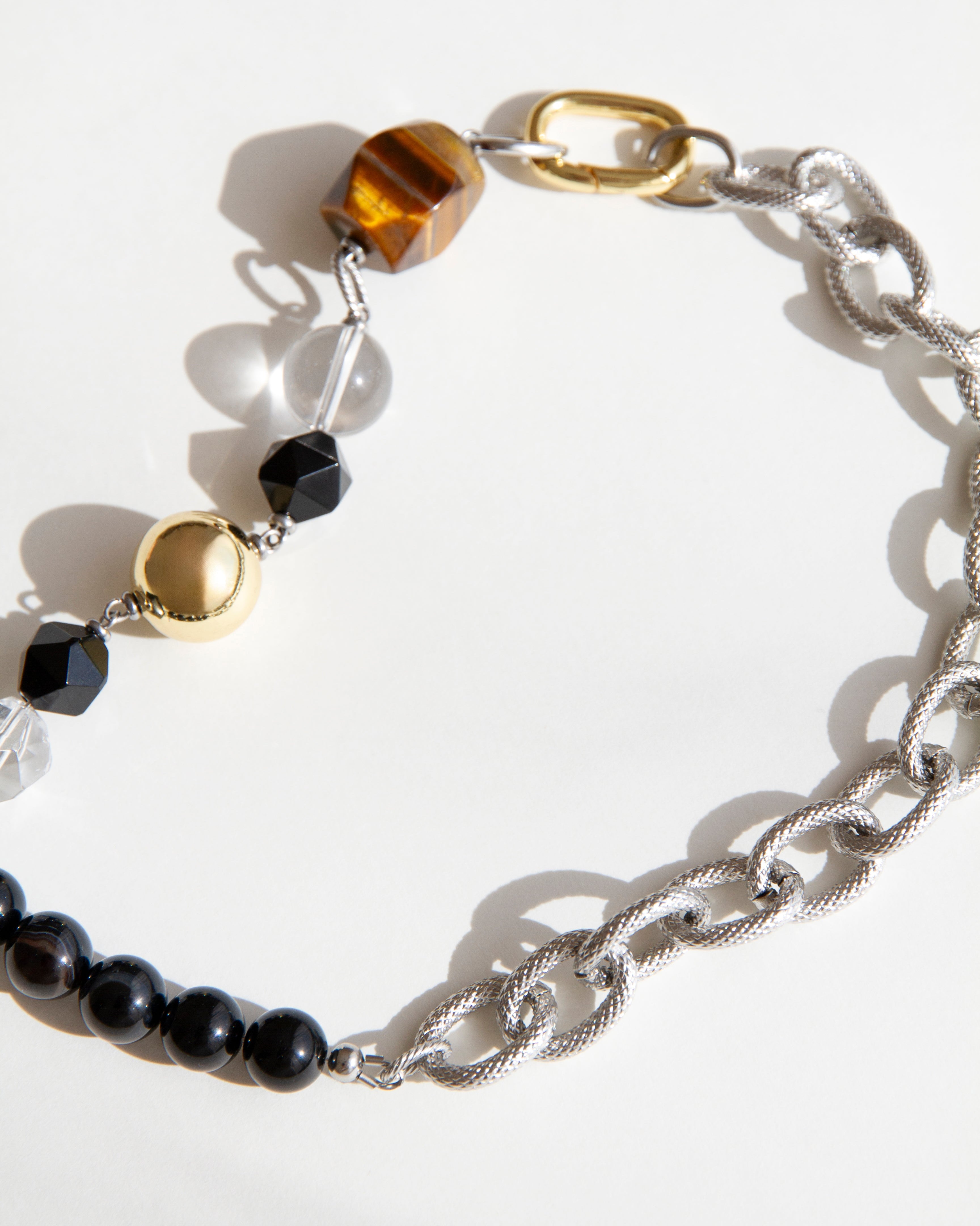 Tiger Eye Necklace featuring bold tiger eye bead, agate, clear quartz, and asymmetrical chain design with mixed gold and silver details.